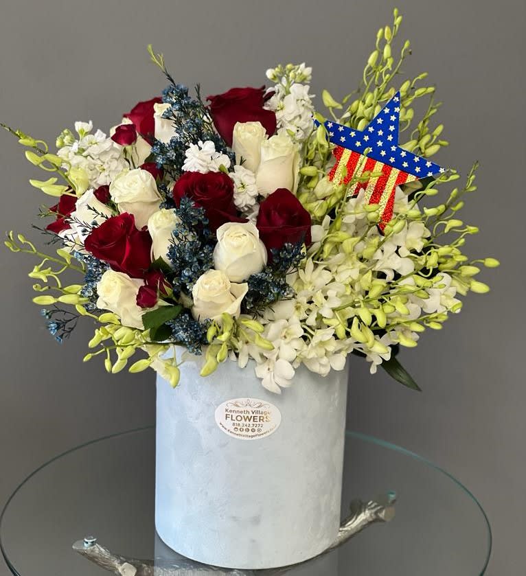 Red and white roses in a white hat box with a patriotic star decoration.