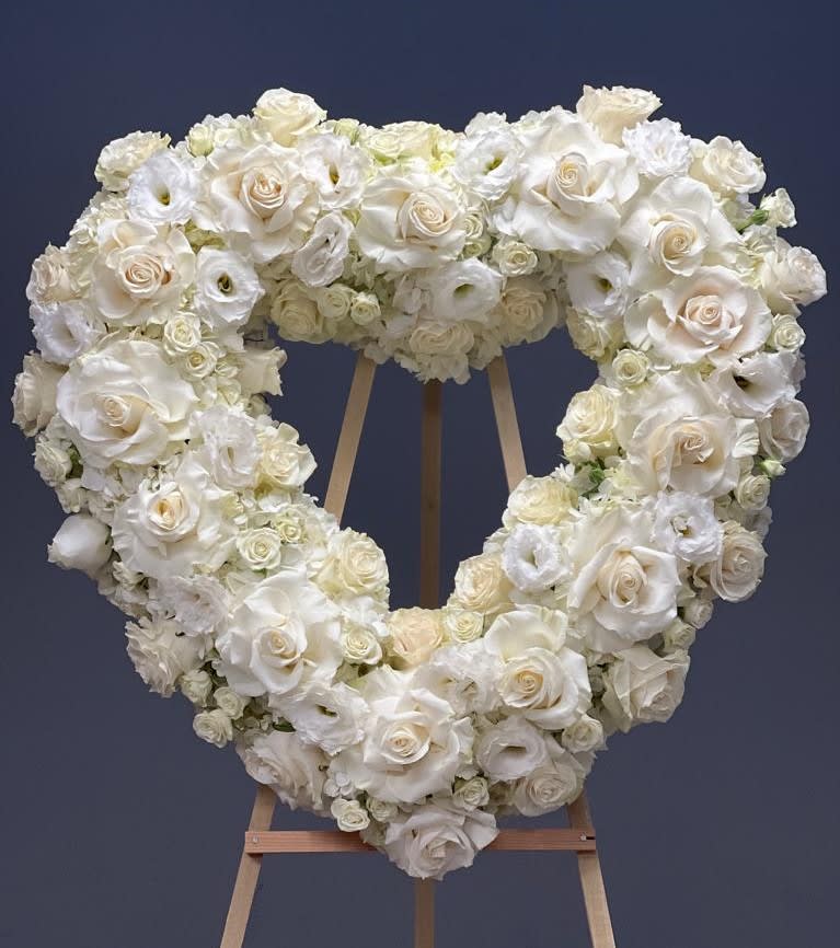 Heart-shaped white floral wreath on a wooden easel