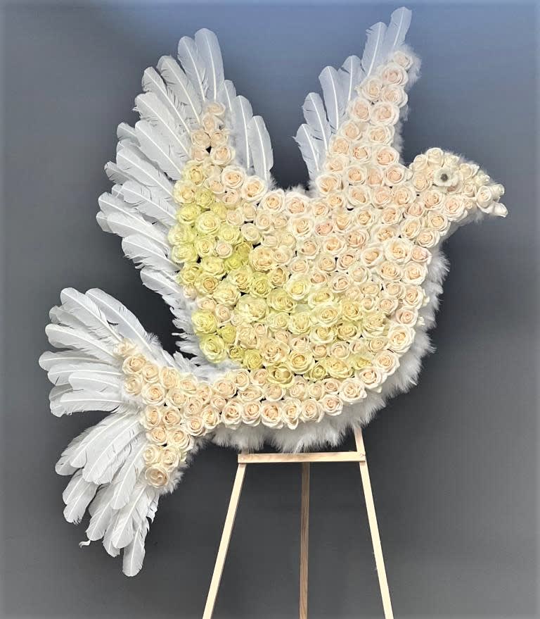 White feathered dove-shaped floral tribute on an easel
