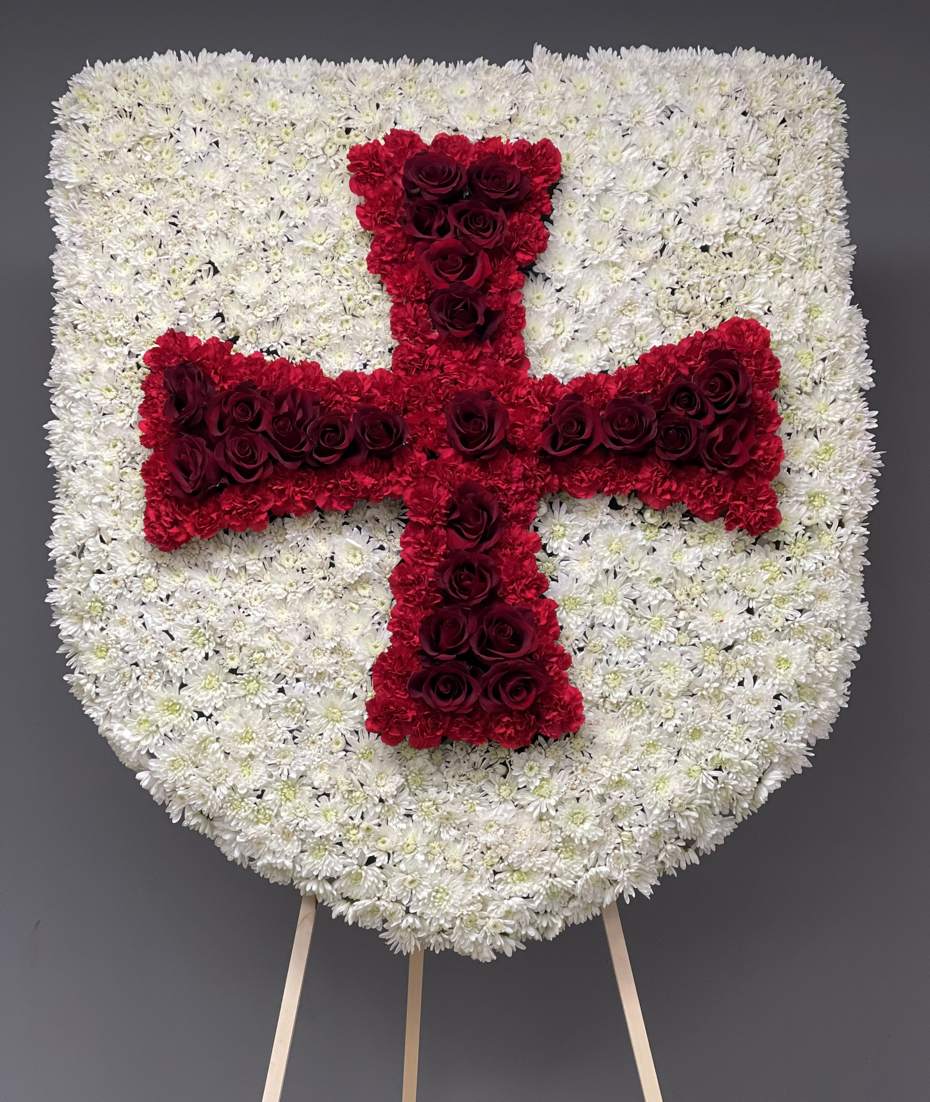Heart-shaped floral tribute with a red cross on a white flower background