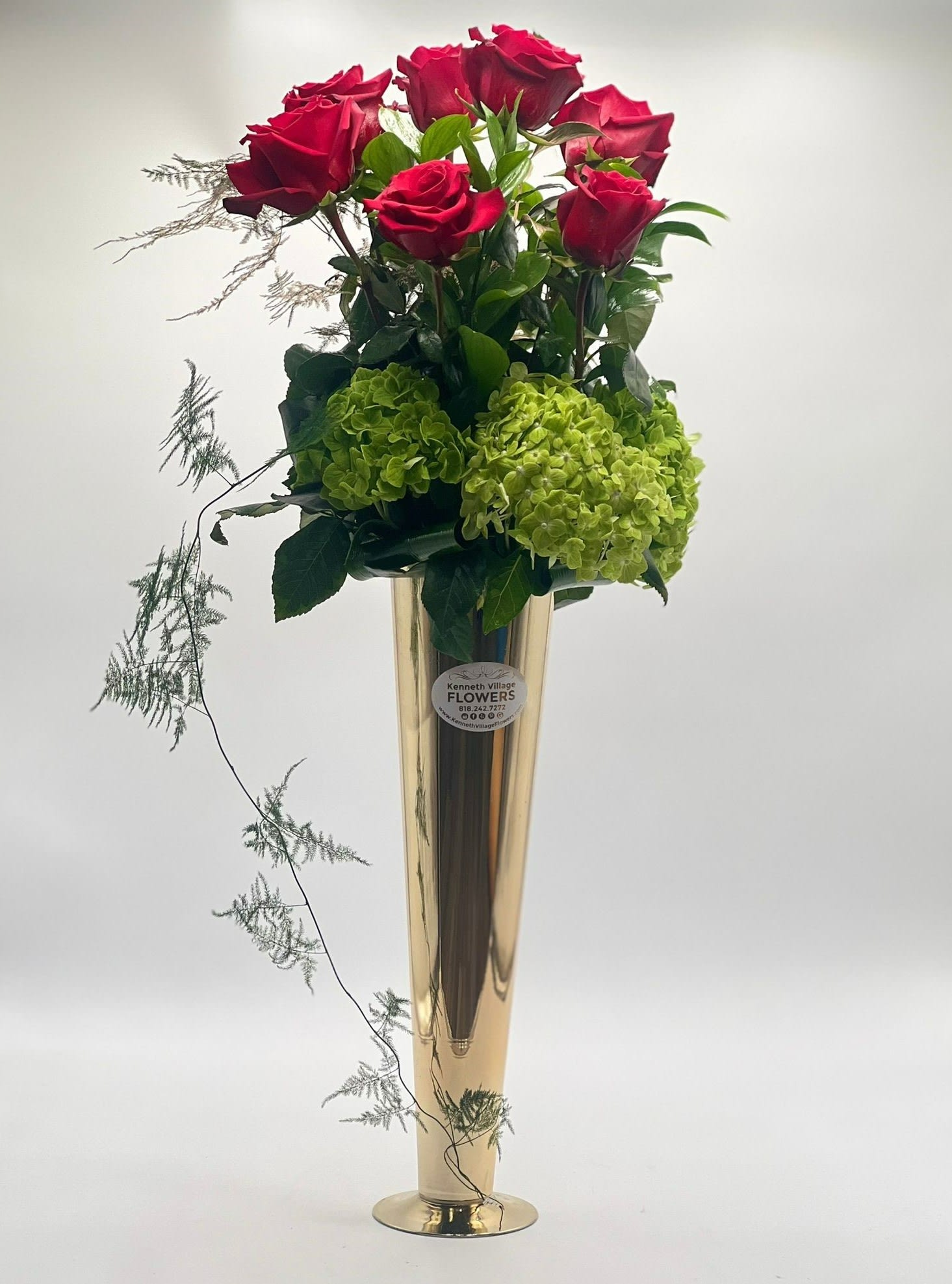 Tall vase arrangement with red roses and green hydrangeas