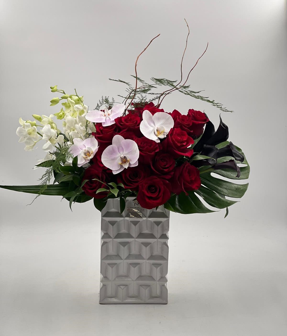 Red roses and white orchids in a tall geometric vase