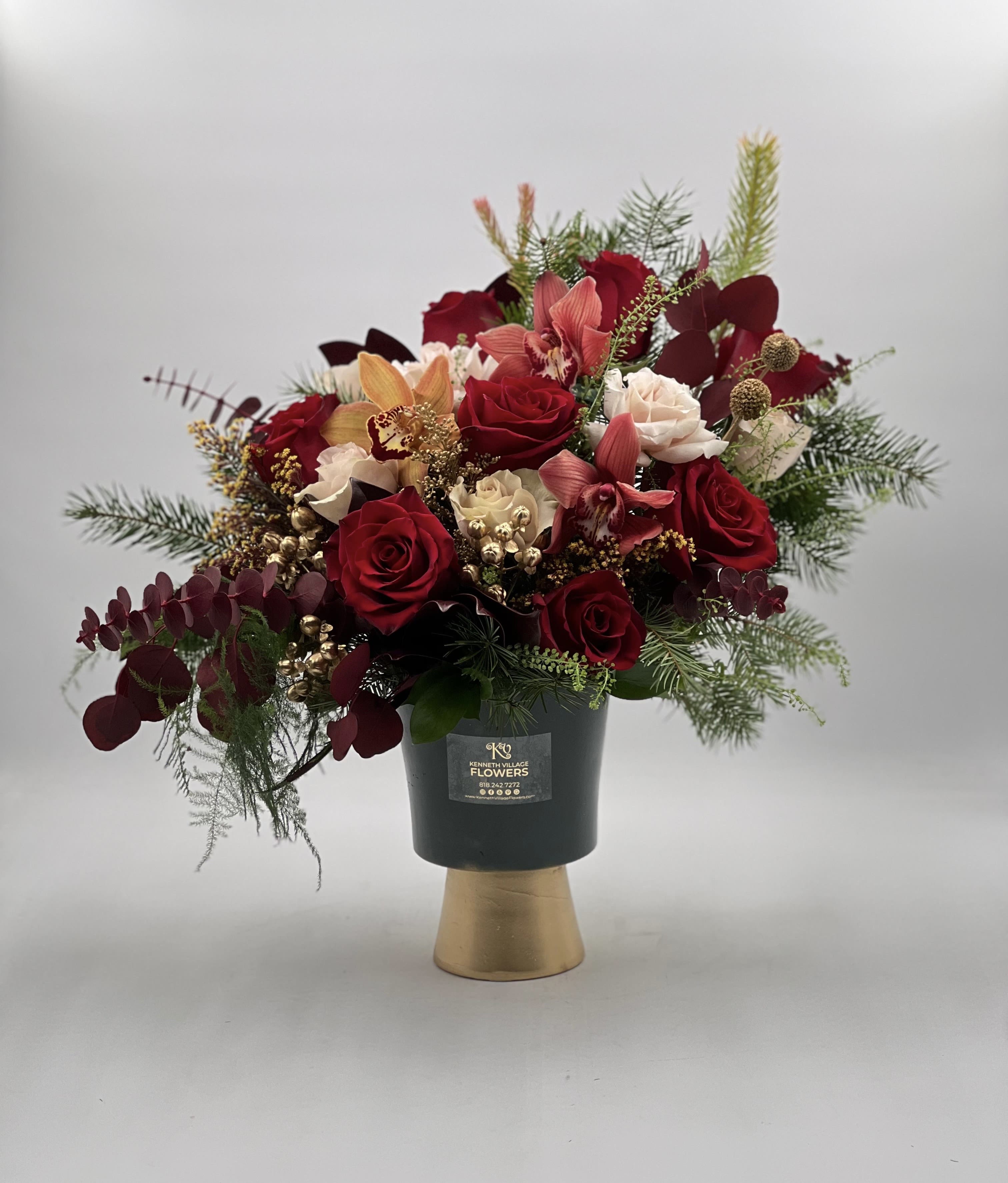 Red roses and pink orchids in a black vase with gold base
