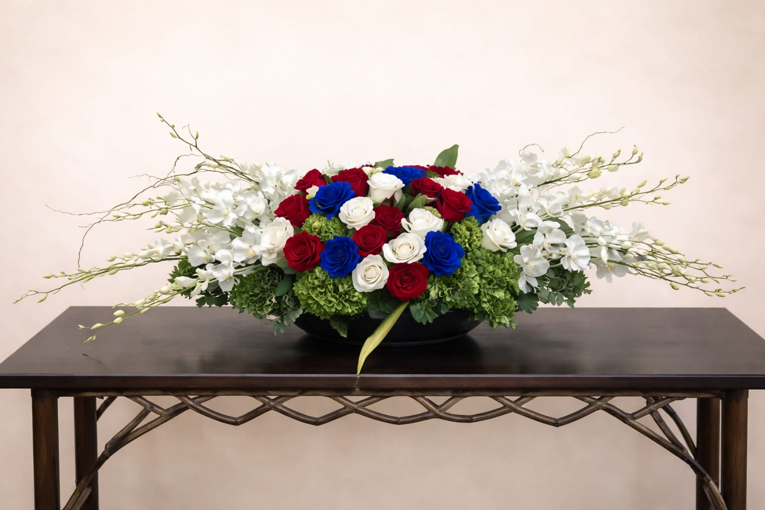 Low floral centerpiece with red, white, and blue roses and white orchids