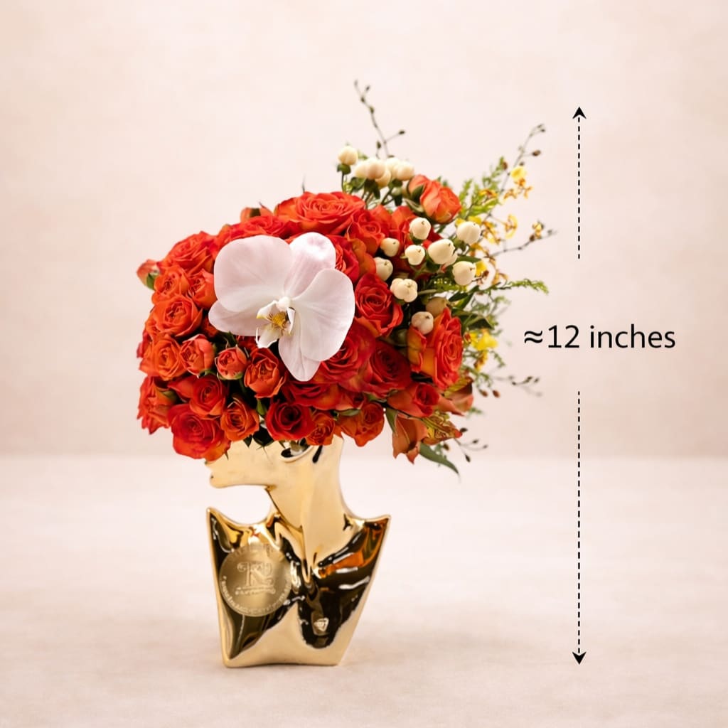 Red rose arrangement in a gold vase with a white orchid accent