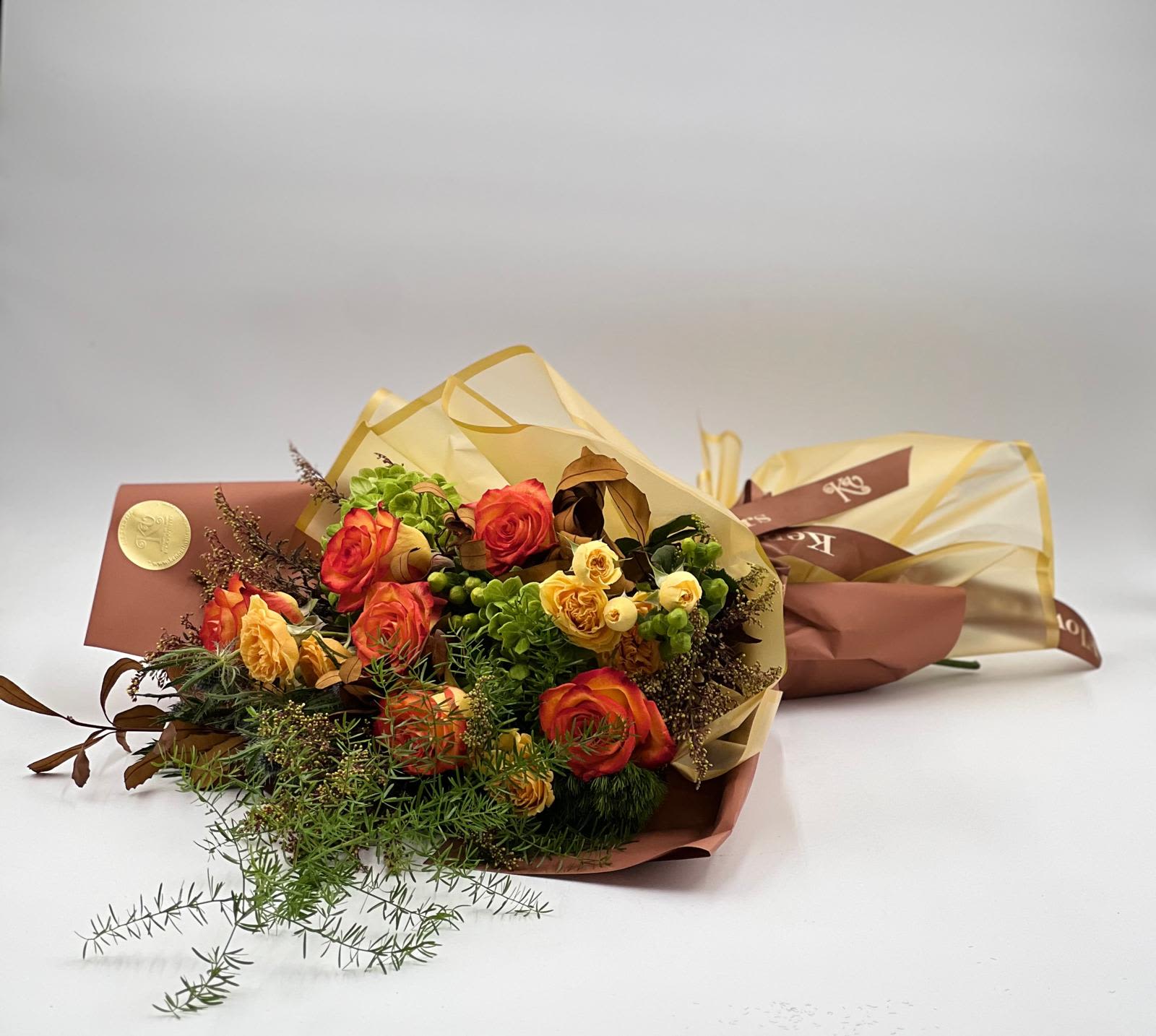 Bouquet of orange and yellow roses wrapped in tan paper