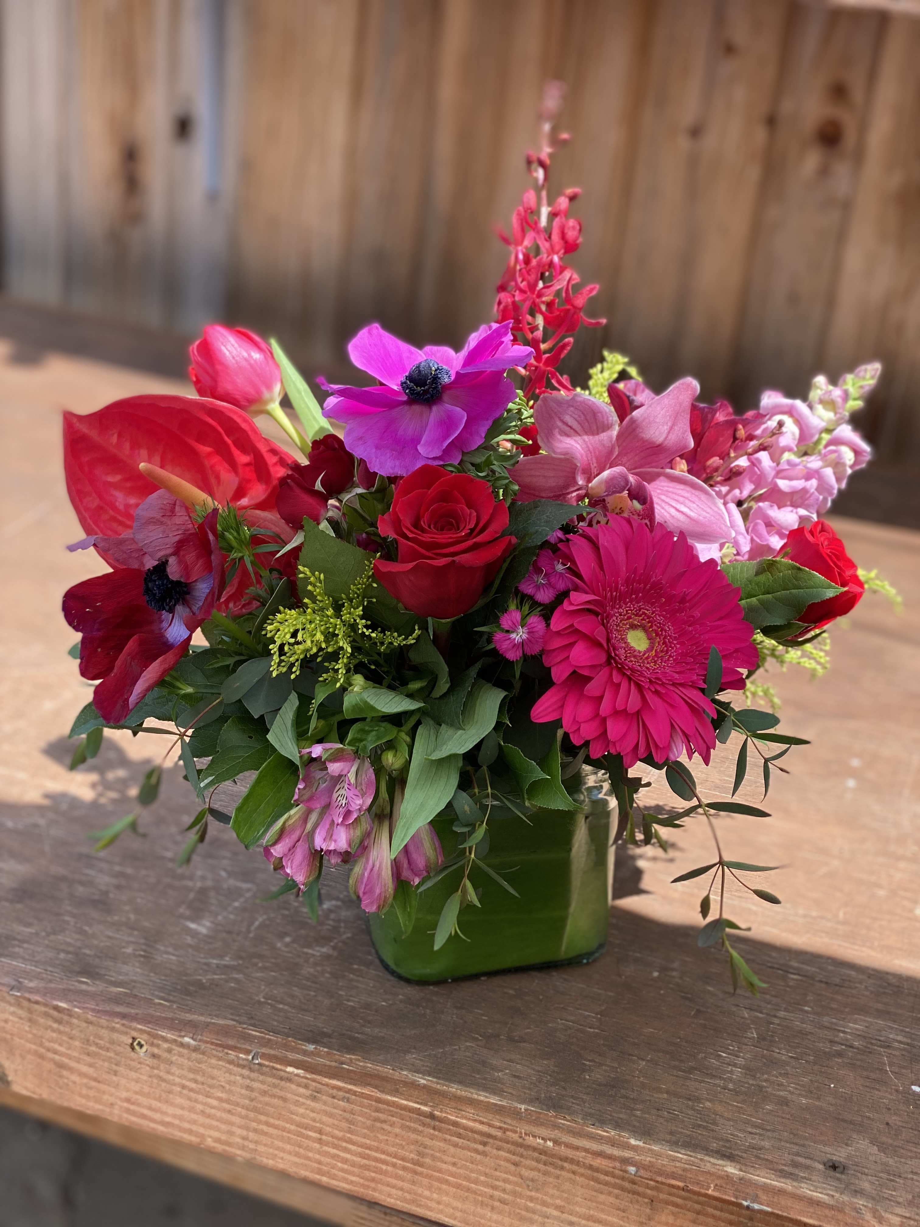 Bright pink and red mixed bouquet in a green glass vase