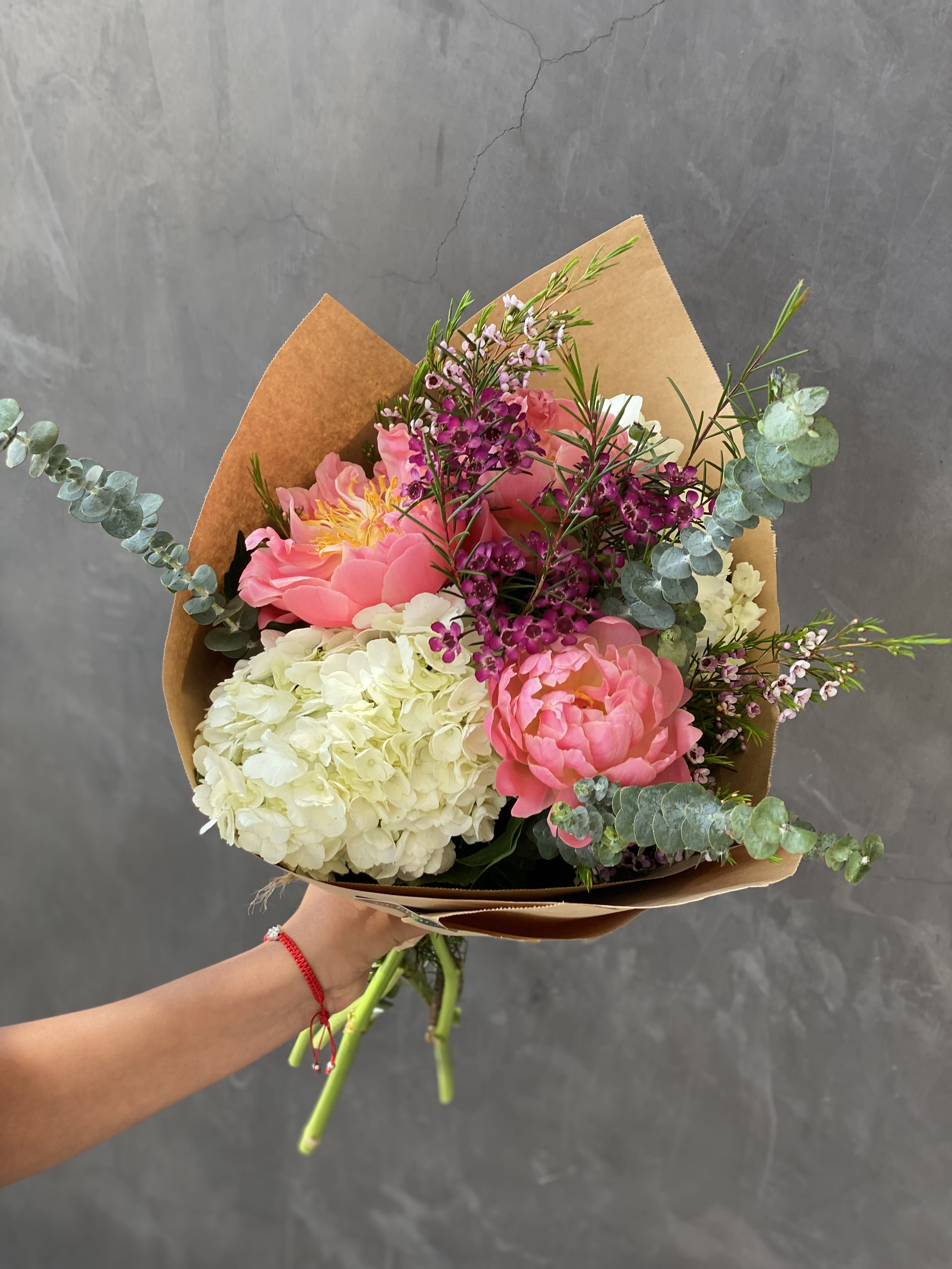 Pink peonies and white hydrangea bouquet with eucalyptus in brown paper
