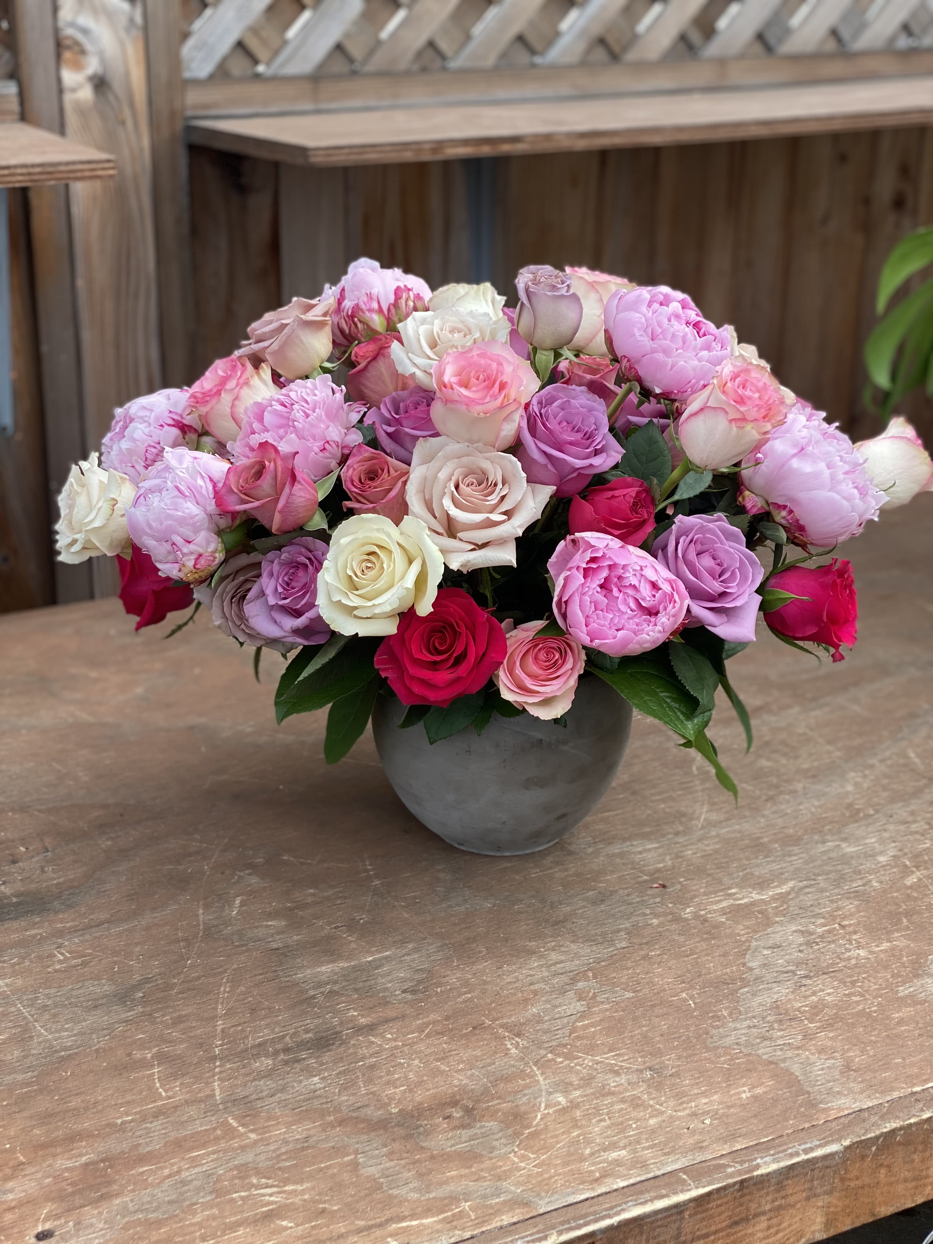 Mixed pink and white roses arranged in a gray vase