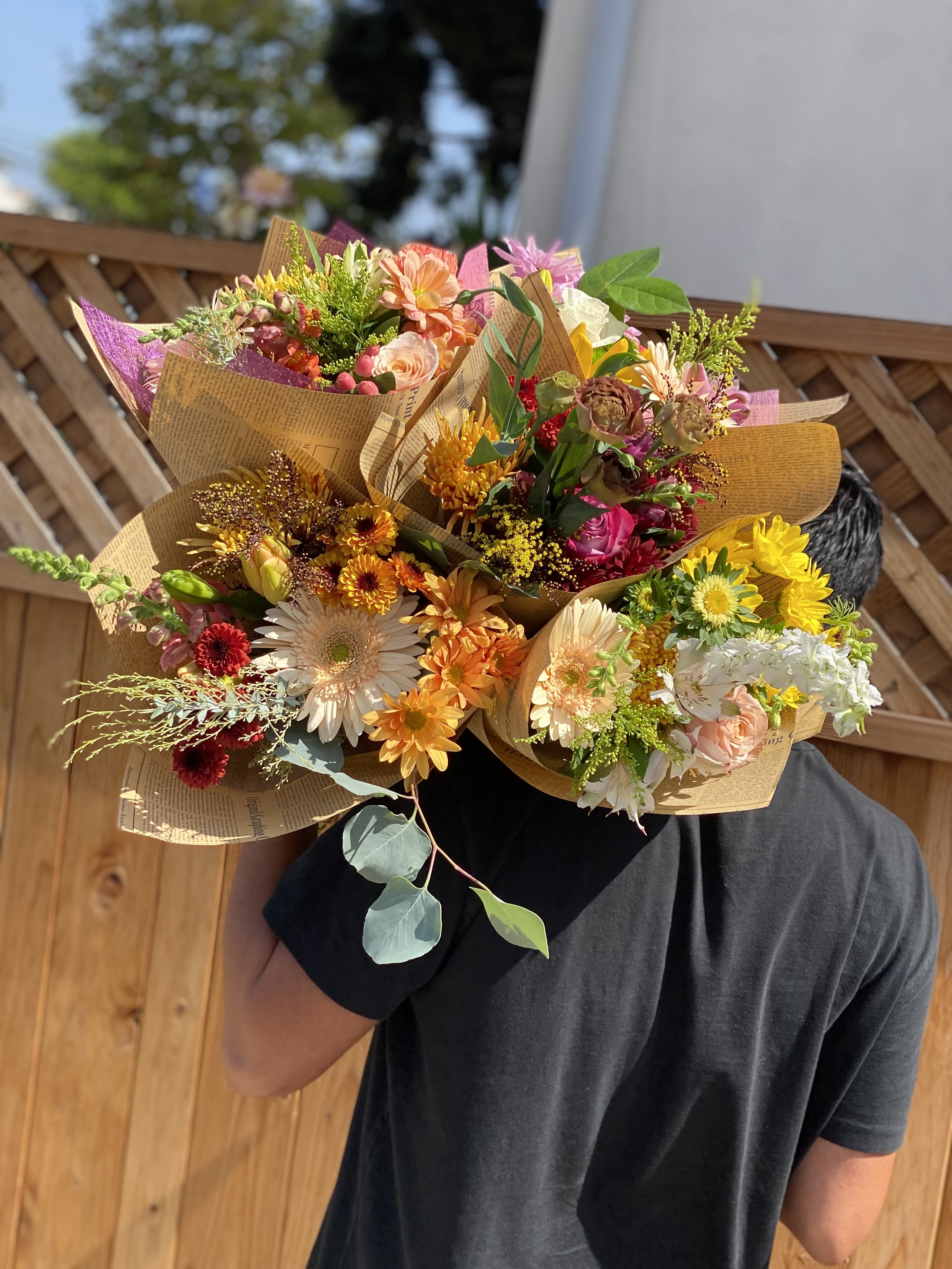 Person holding several colorful mixed flower bouquets wrapped in paper