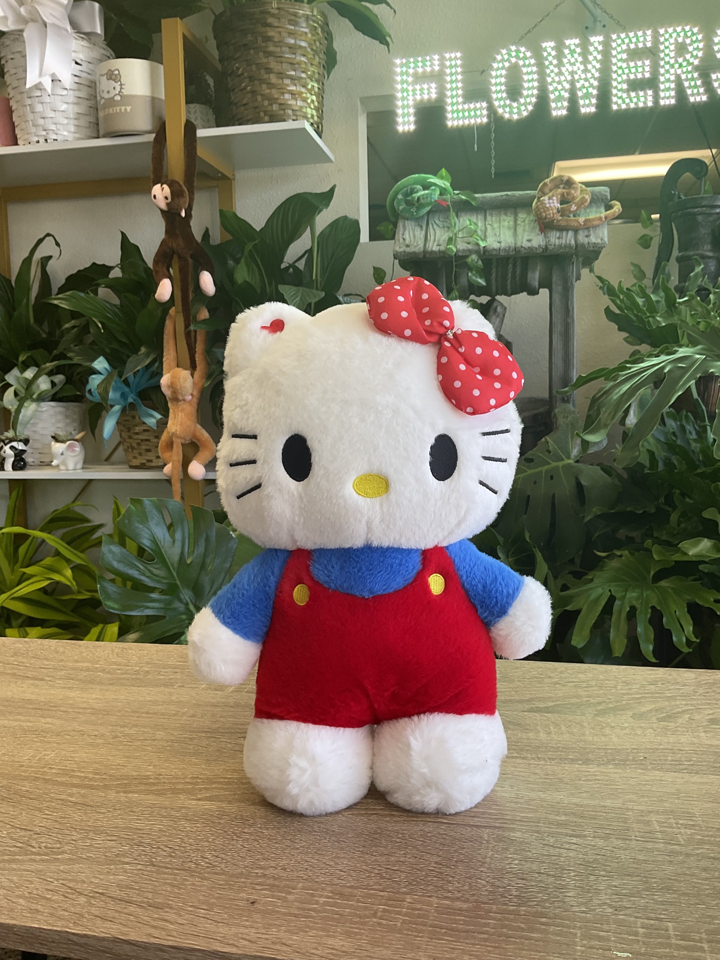 Hello Kitty plush toy in red overalls with a polka-dot bow
