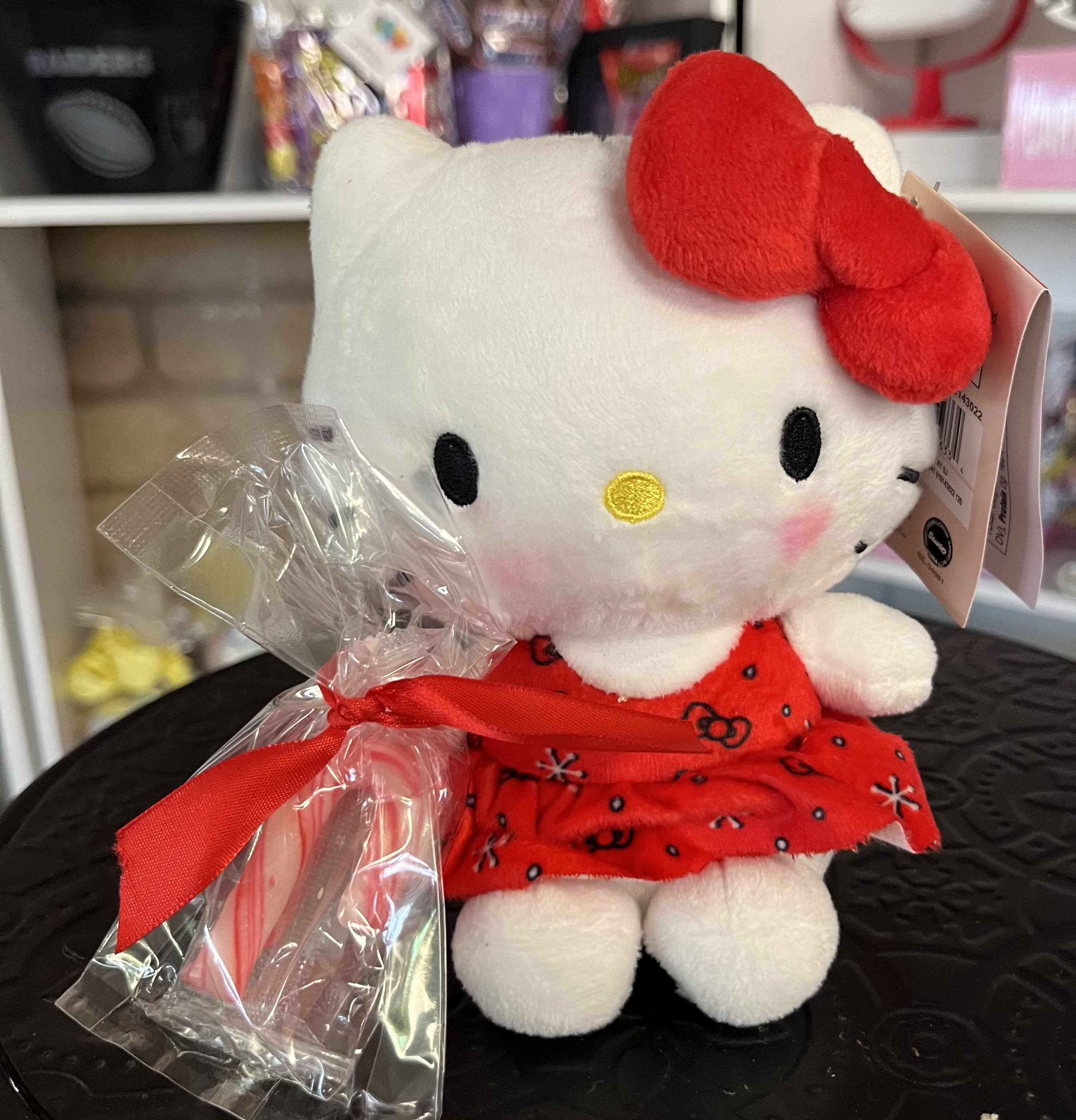 Hello Kitty plush toy in a red dress with a candy cane and ribbon