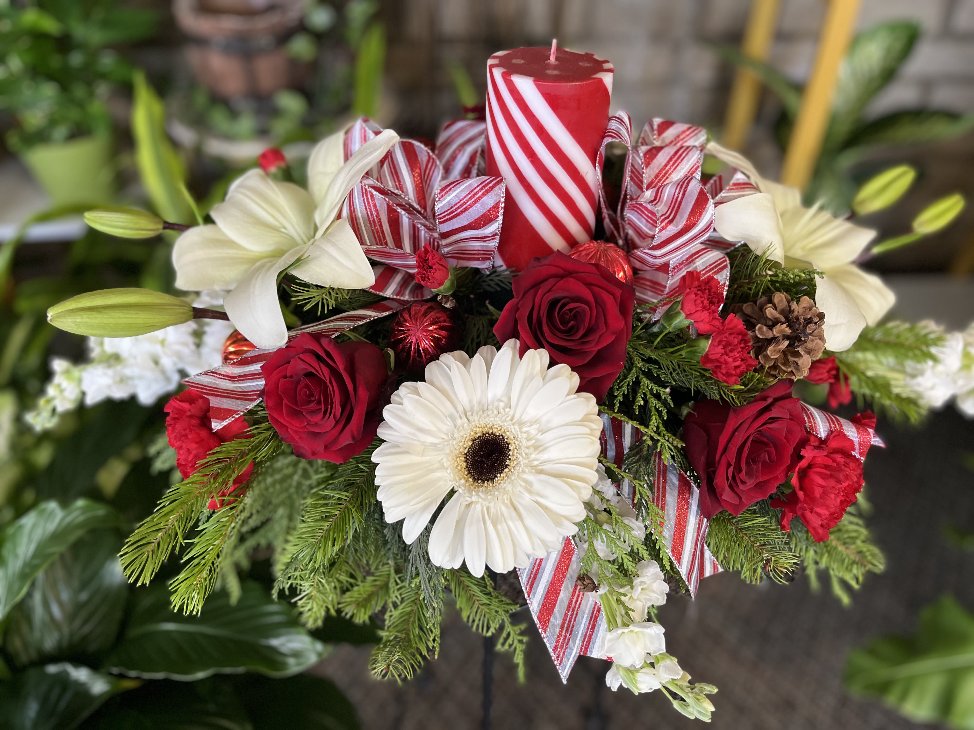 Red roses and white lilies arranged with a candle and striped ribbon