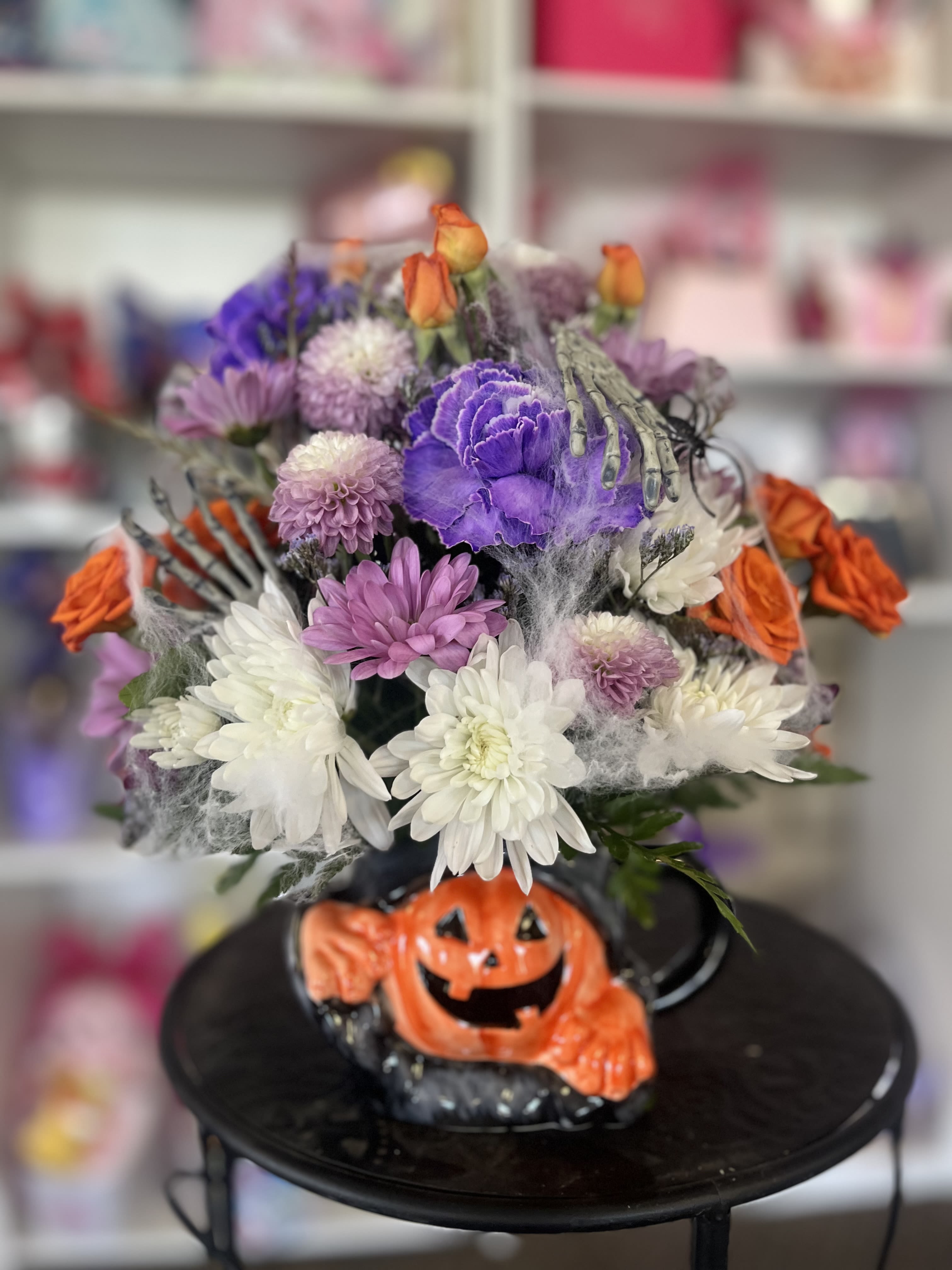 Halloween bouquet with purple, white, and orange flowers in a pumpkin base