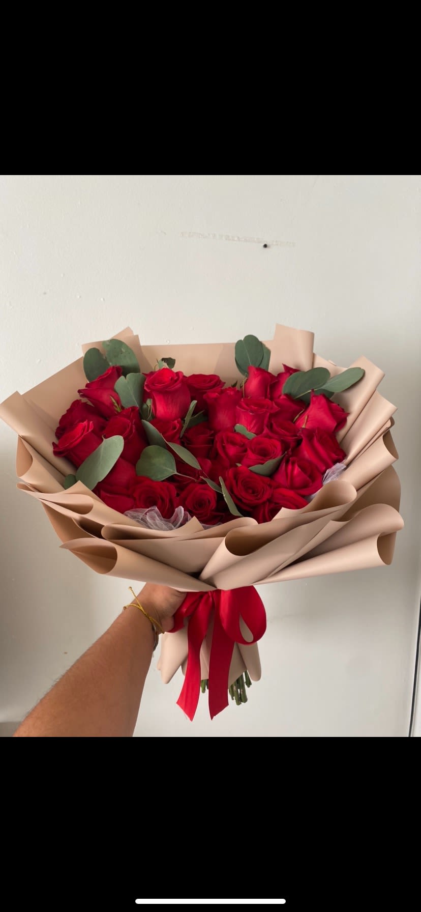 Bouquet of red roses wrapped in beige paper with a red ribbon