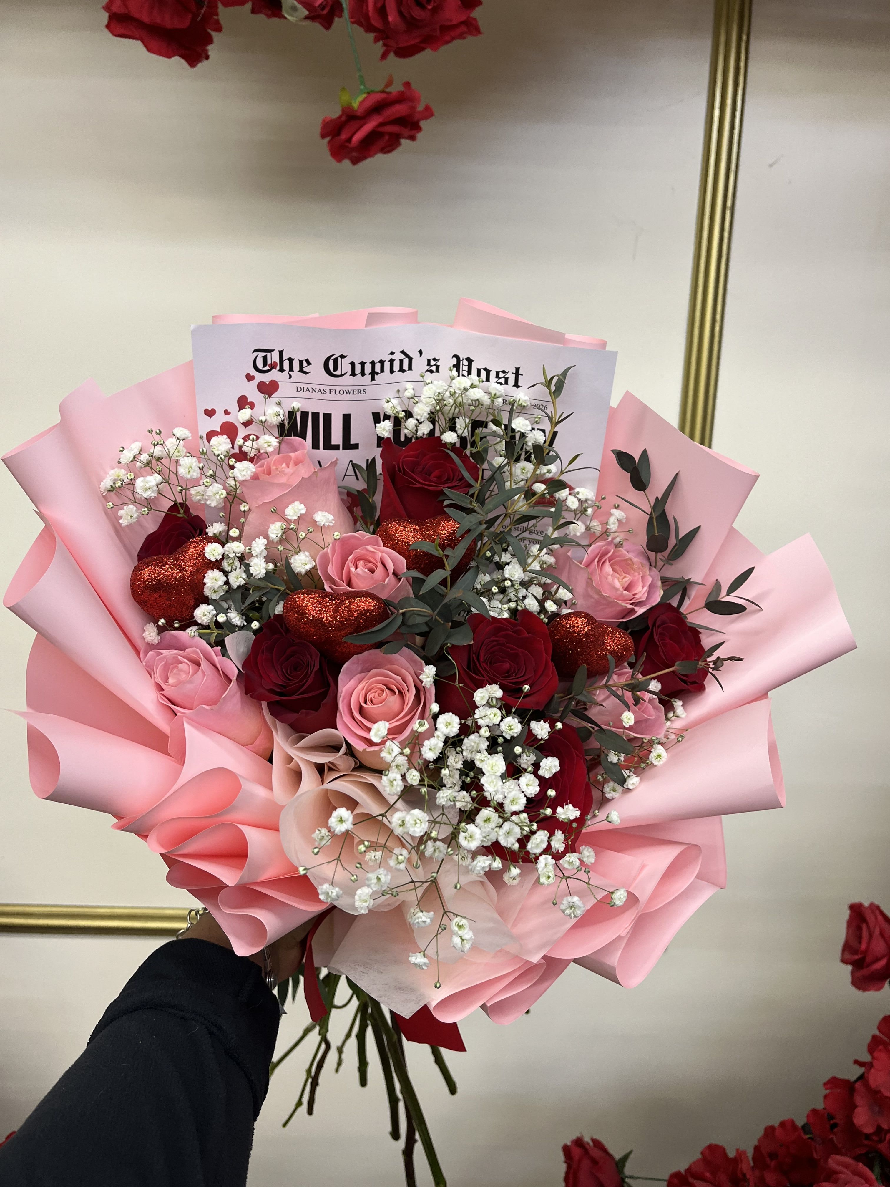 Bouquet of red and pink roses with baby’s breath in pink wrapping