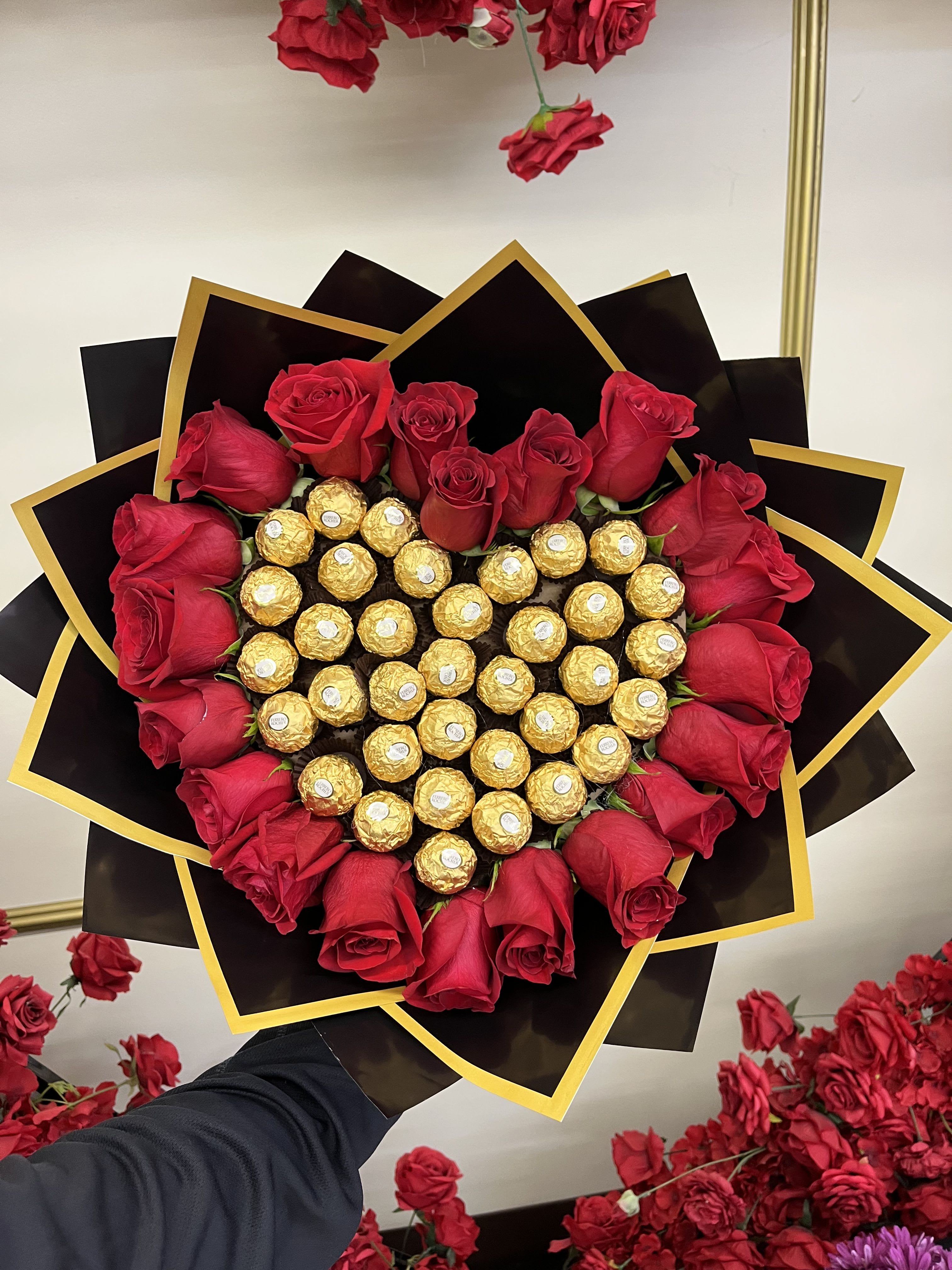 Heart-shaped bouquet of red roses and gold-wrapped chocolates