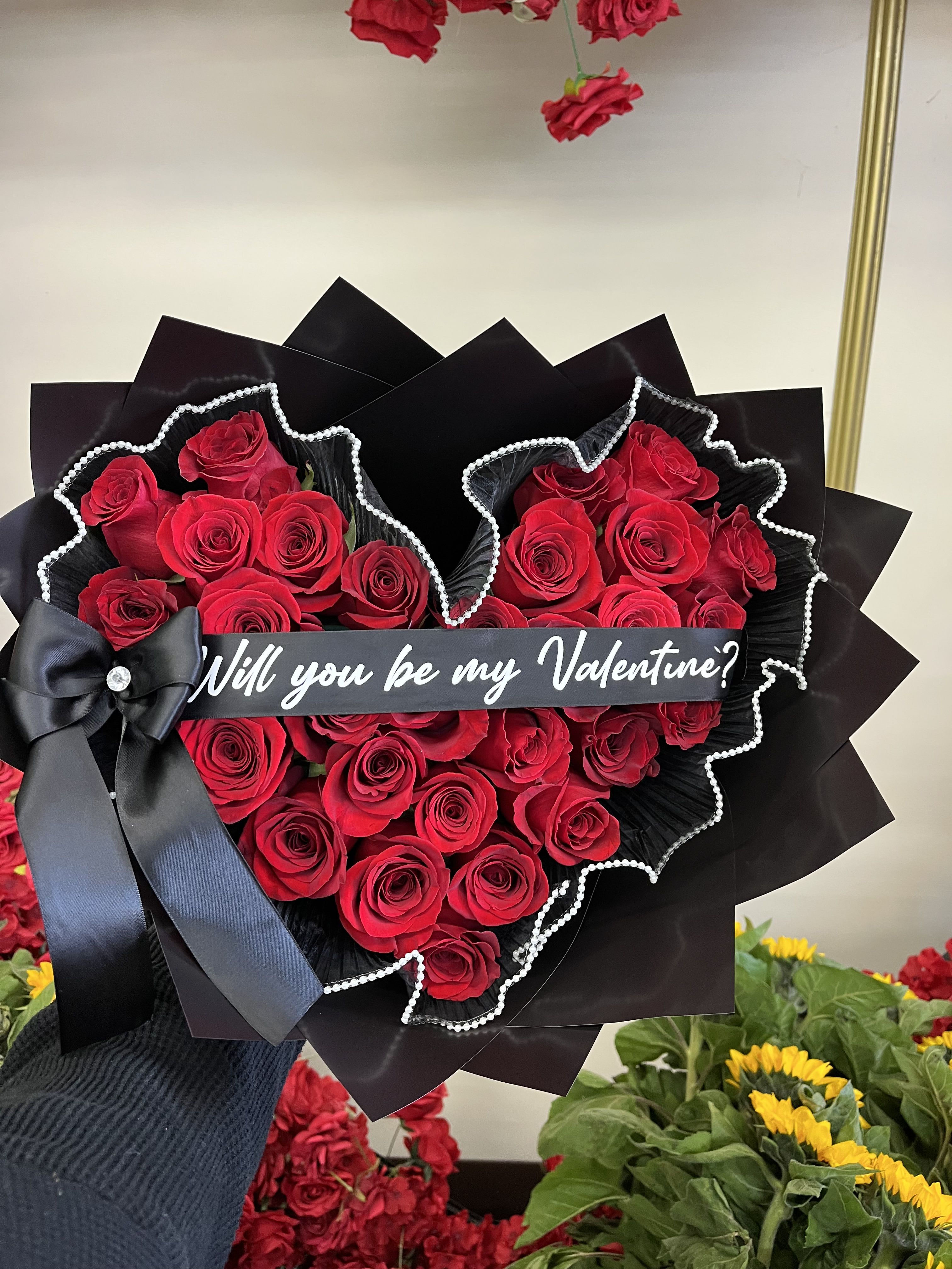 Heart-shaped bouquet of red roses with a black ribbon and Valentine message