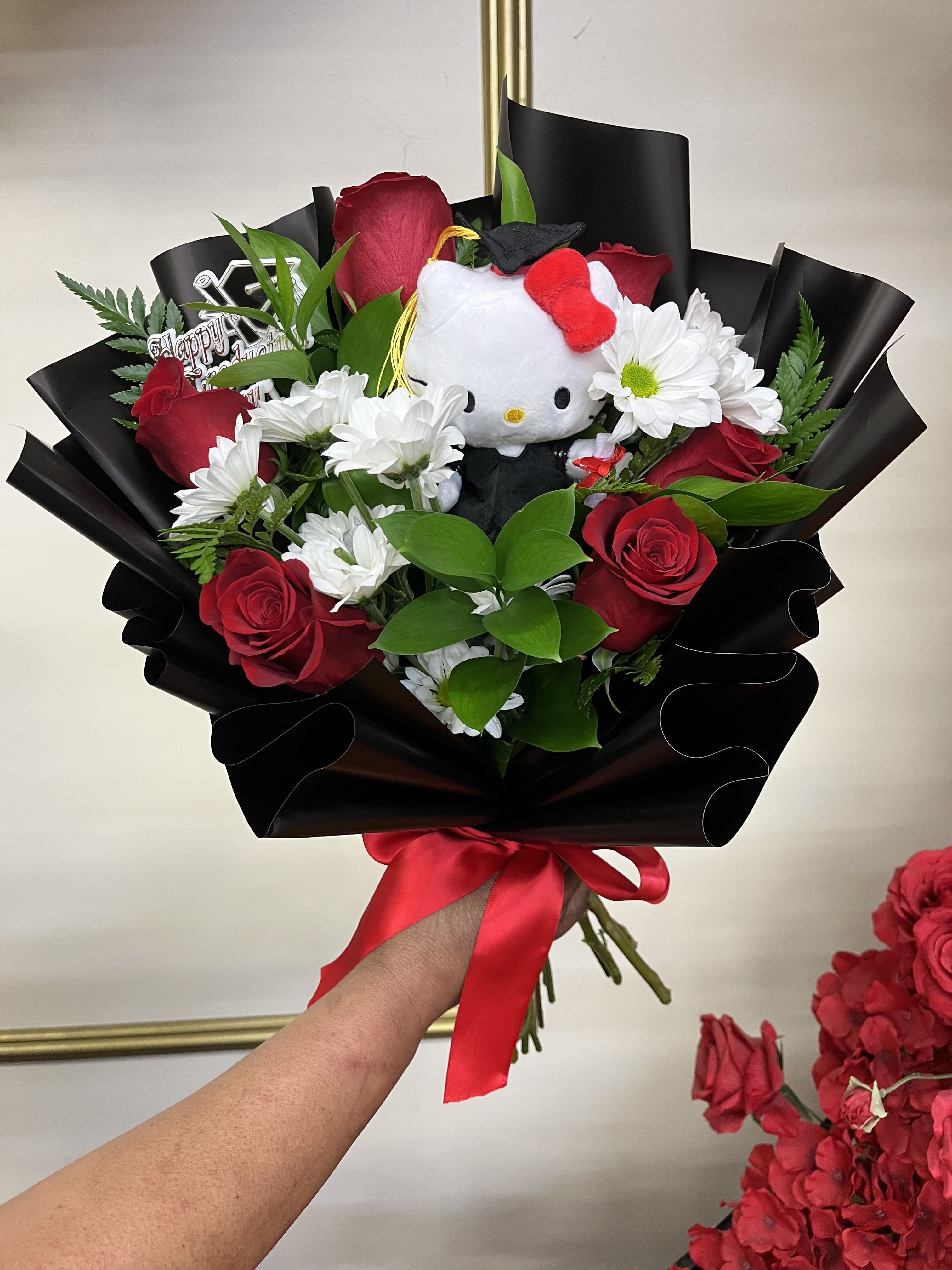 Hello Graduate, Kitty! bqt - Celebrate her big accomplishment with the sweetest graduation bouquet featuring luxurious red roses, soft pom pom daisies, and an adorable Hello Kitty graduation plush. A perfect mix of cute, classic, and celebratory for your favorite graduate. 