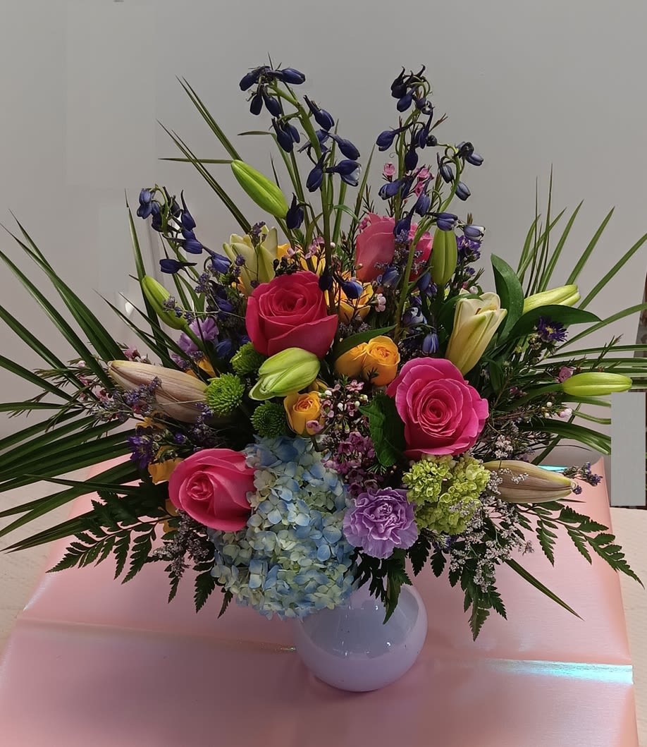 Colorful mixed bouquet in a white vase with roses, lilies, and hydrangea