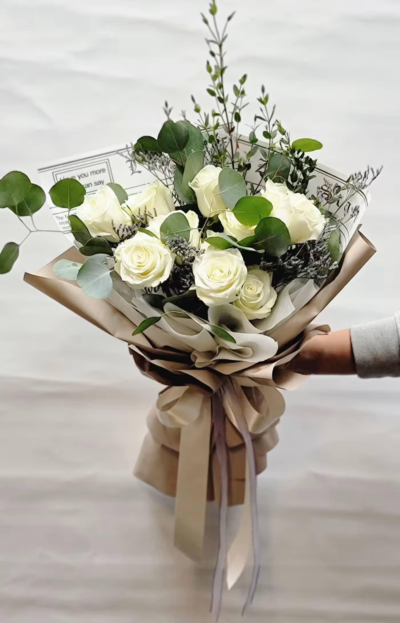 Bouquet of white roses with eucalyptus in tan wrapping