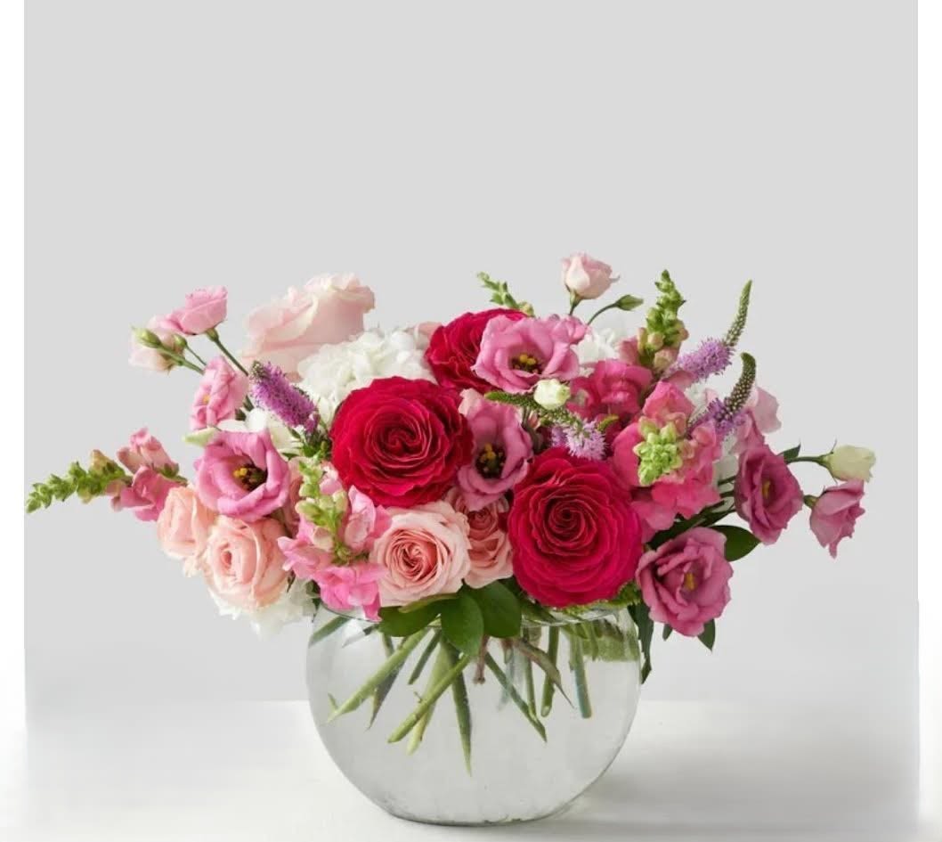 Pink and red mixed flower arrangement in a clear glass vase