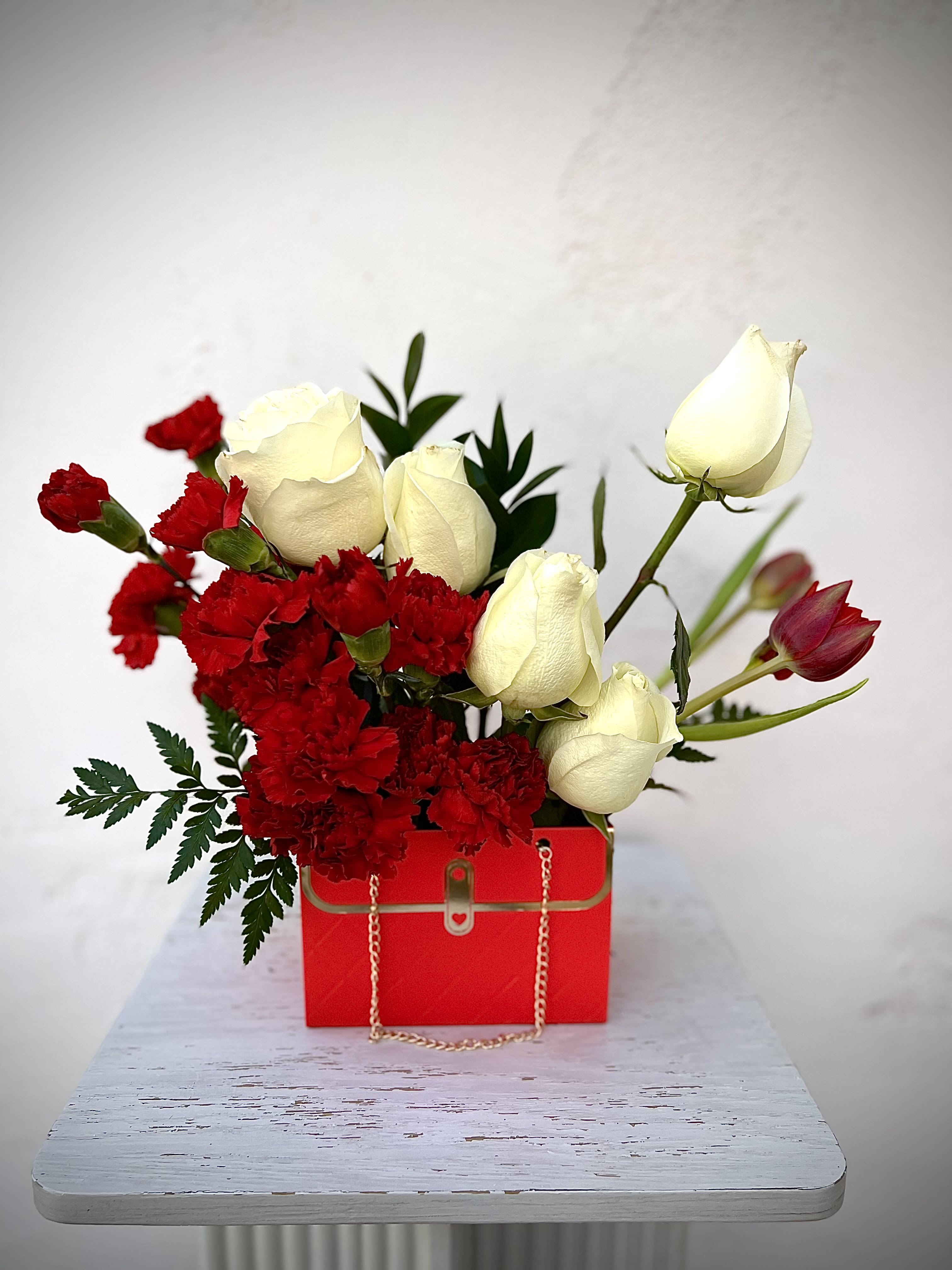 Red carnations and white roses in a red gift box