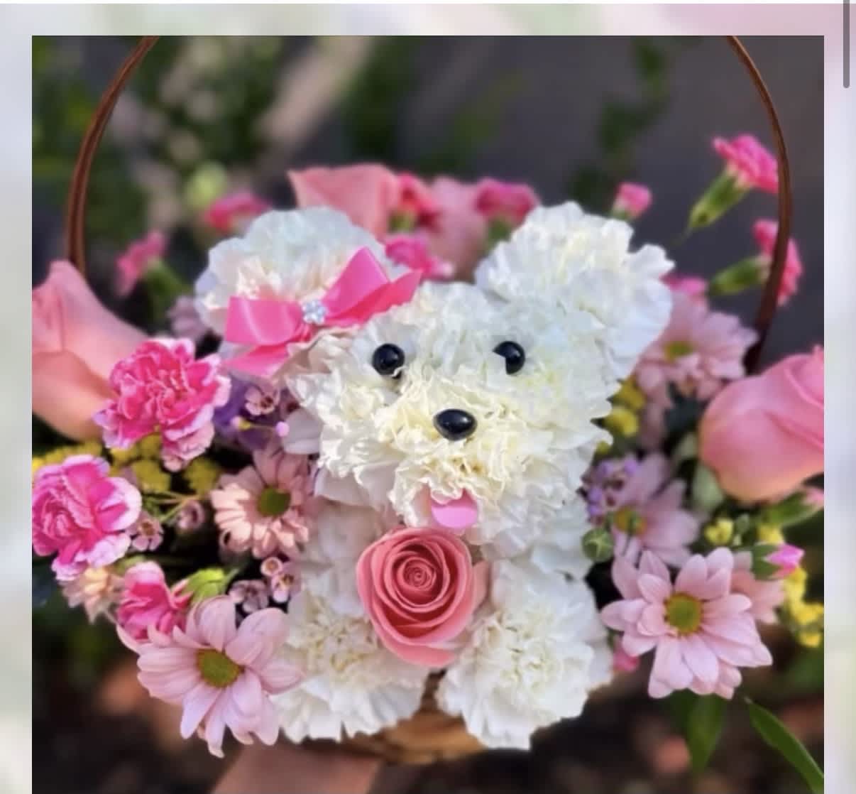 Pink and white flower arrangement shaped like a teddy bear in a basket