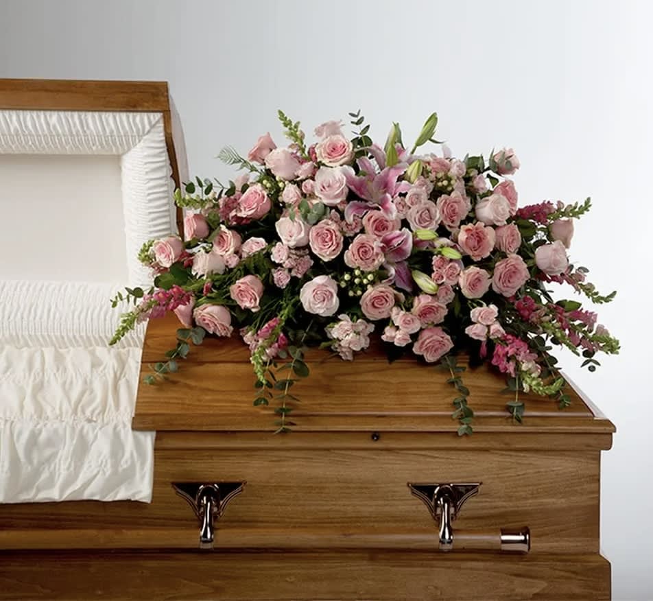 Pink rose and lily casket spray on a wooden casket