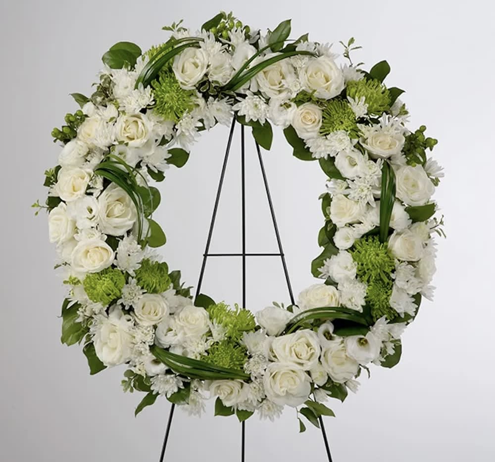 White floral wreath on a black easel with green accents