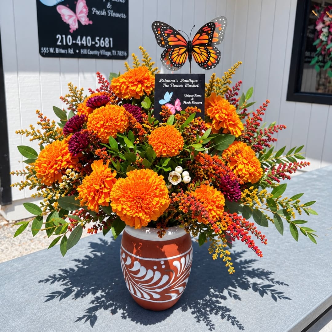 Orange and purple floral arrangement in a painted ceramic vase with butterfly decor