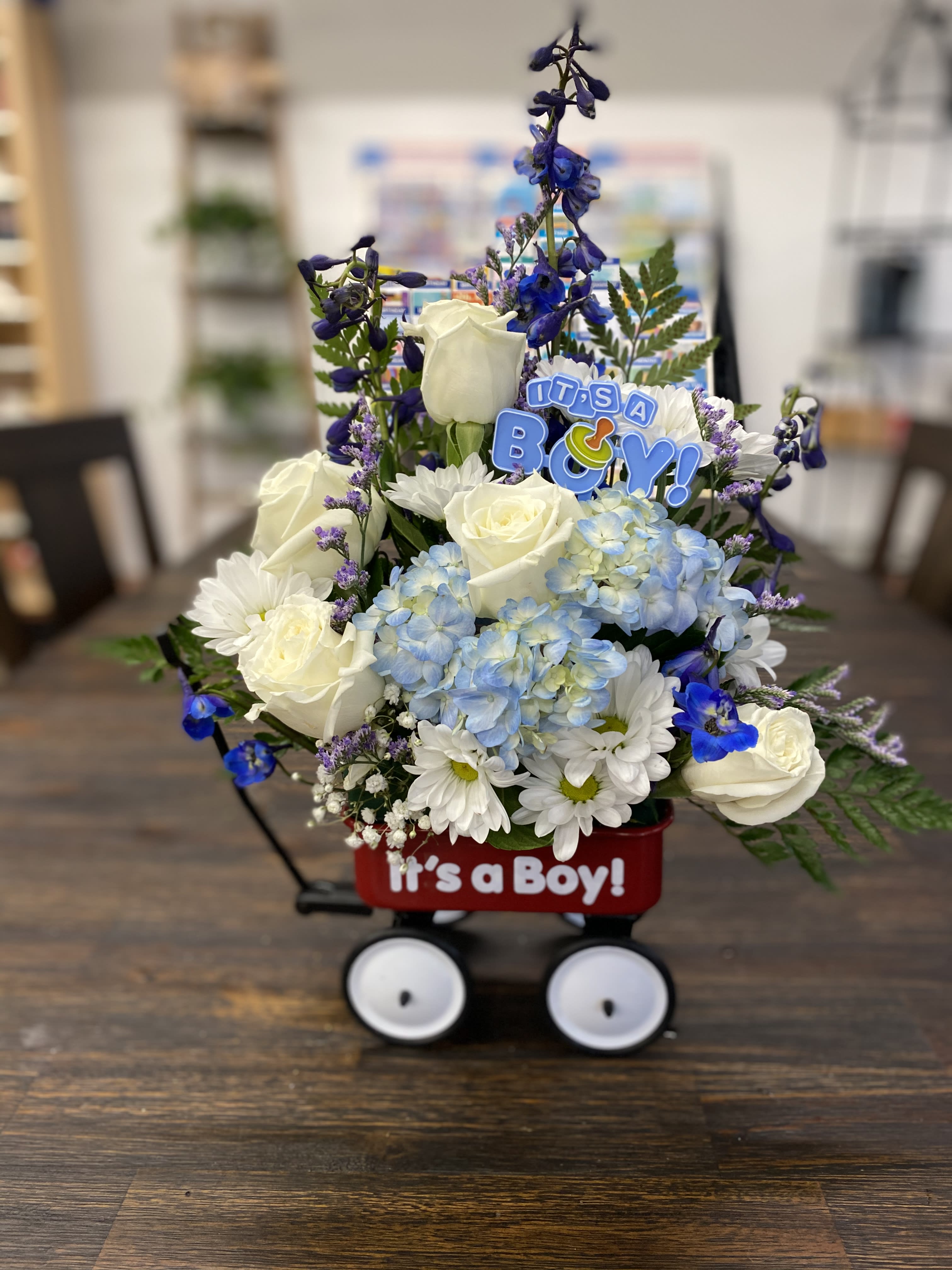 Blue and white flower arrangement in a wagon with an "It's a Boy!" sign