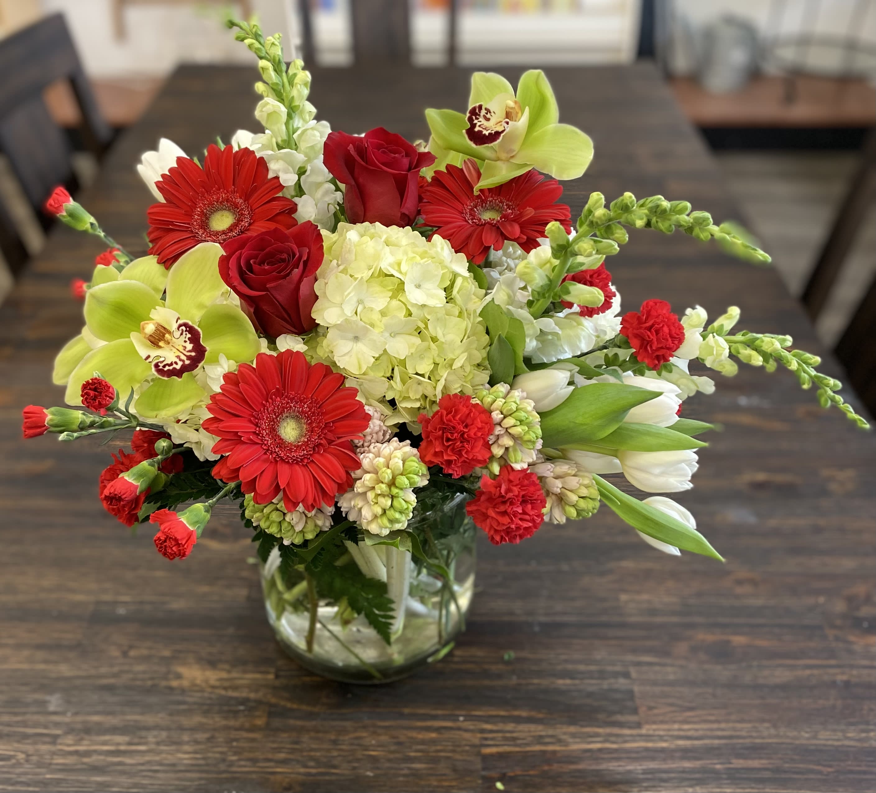 Red and green mixed flower arrangement in a glass vase