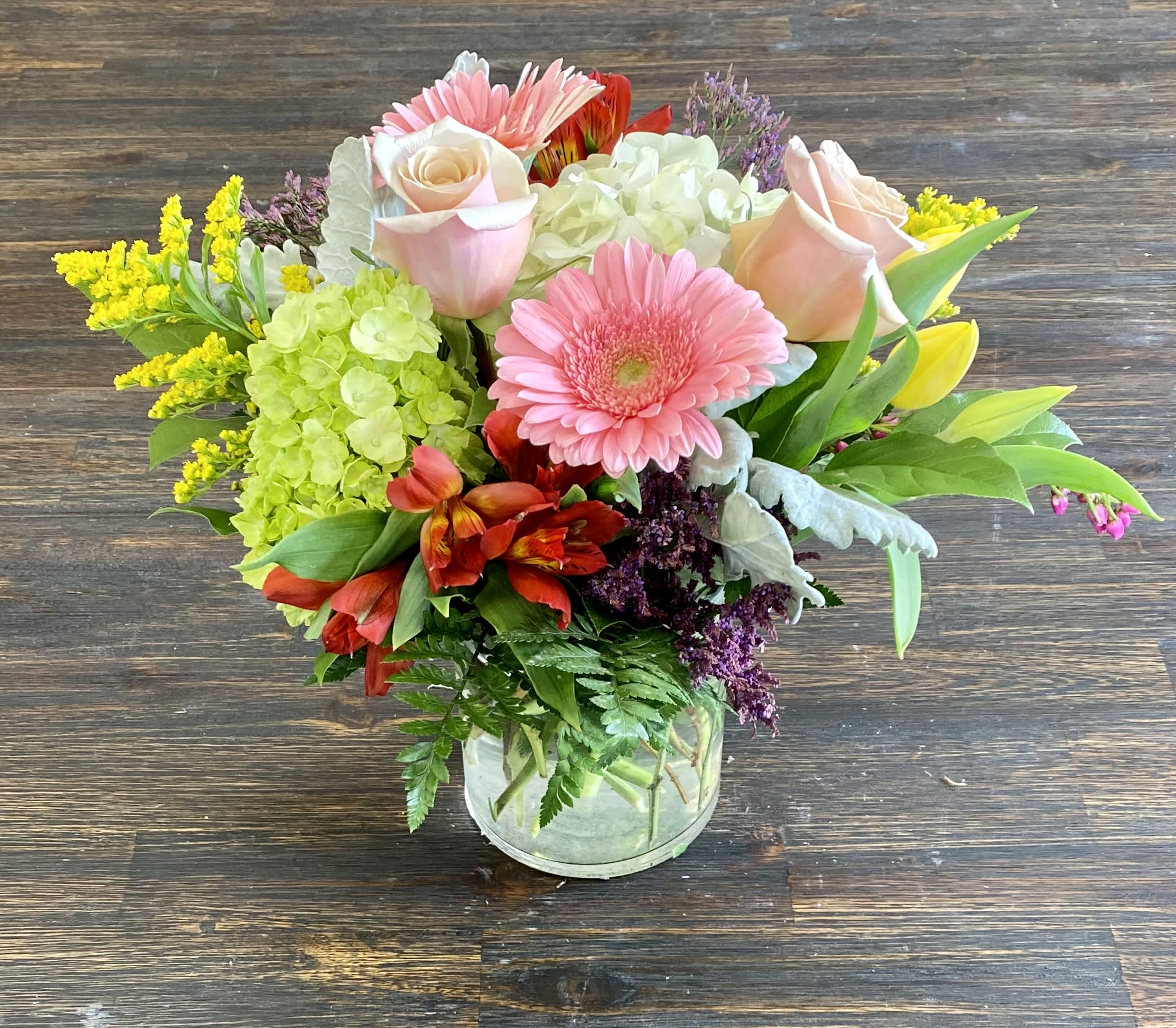 Mixed bouquet of pink roses, gerbera daisies, and hydrangeas in a glass vase