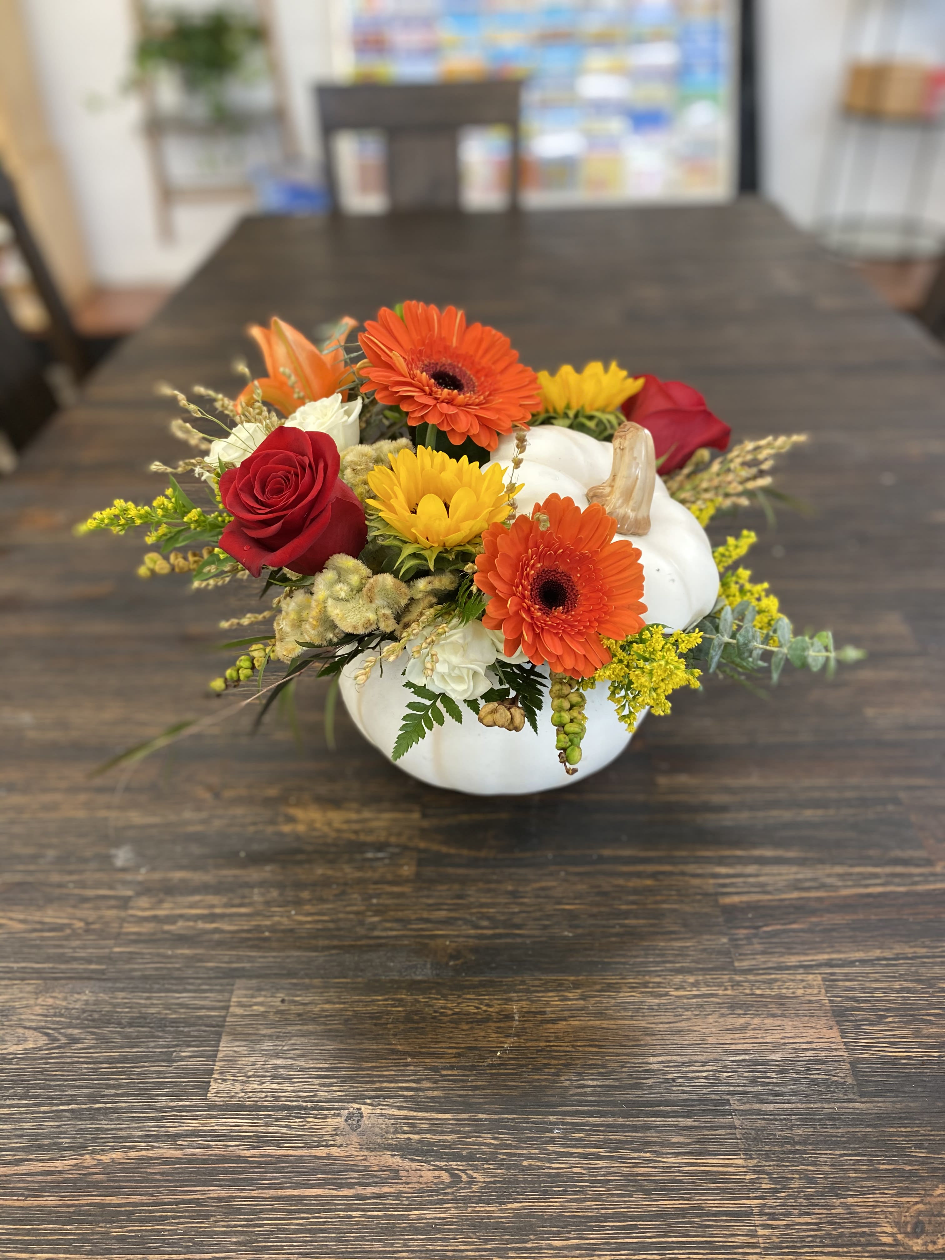 Pumpkin-shaped floral arrangement with orange gerberas, red roses, and yellow blooms