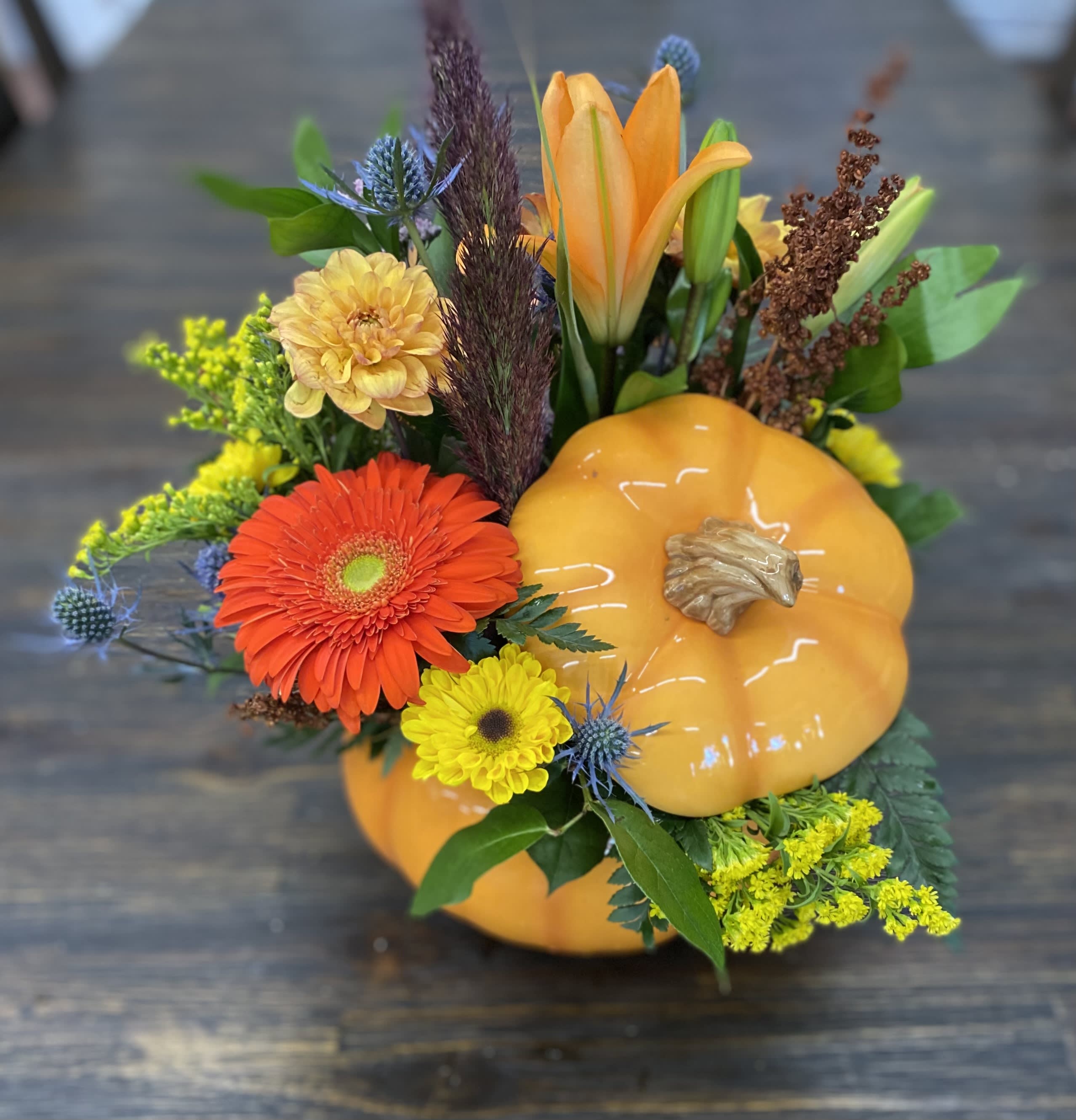 Fall floral arrangement with orange pumpkin decor and mixed blooms