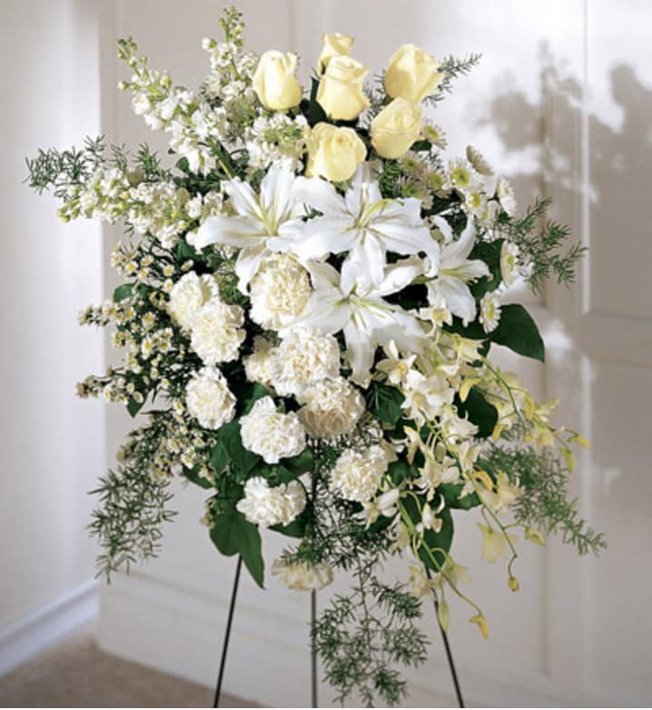 Standing floral spray with white lilies, yellow roses, and white carnations