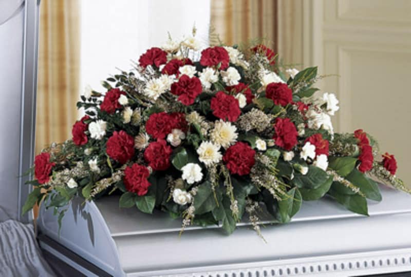 Red and white floral casket spray on a silver casket