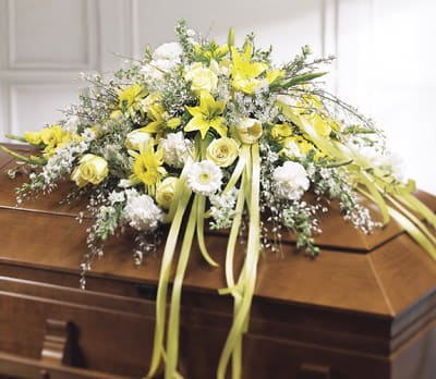 Yellow and white floral spray on a wooden casket
