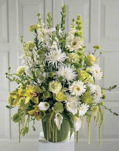 Tall green and white floral arrangement in a ribbed vase