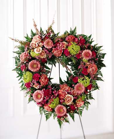 Heart-shaped floral wreath on an easel with pink and red flowers