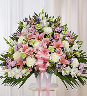 Large pink and white floral spray with a pink ribbon on a stand