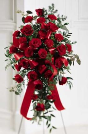 Red rose standing spray with a red ribbon on a white easel