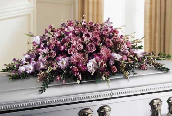 Large pink and purple floral spray on a white casket