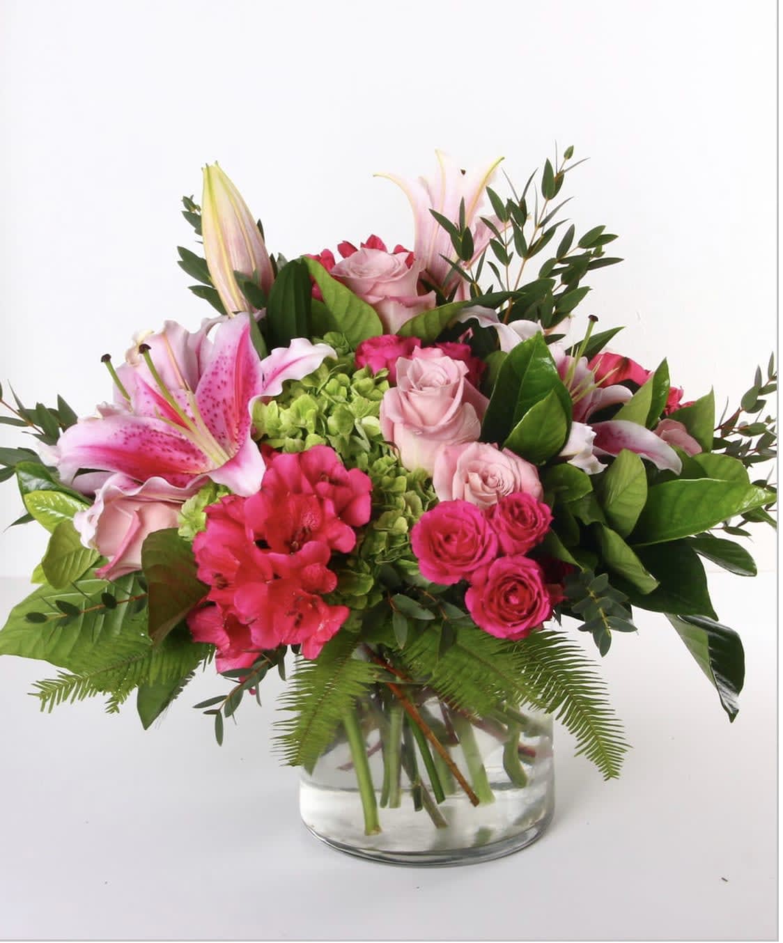 Pink lilies and roses arranged in a clear glass vase