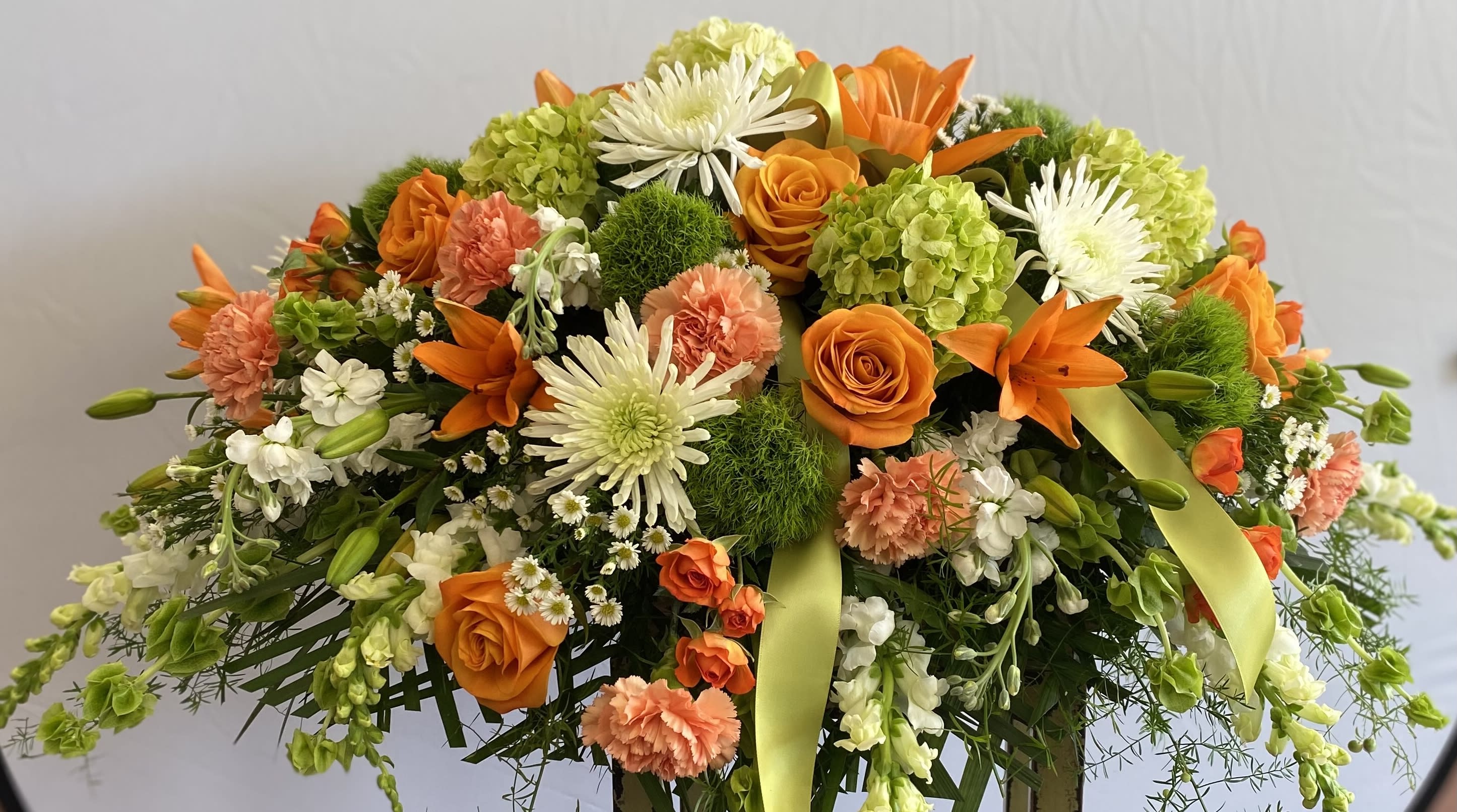 Orange, white, and green floral spray with ribbon accents