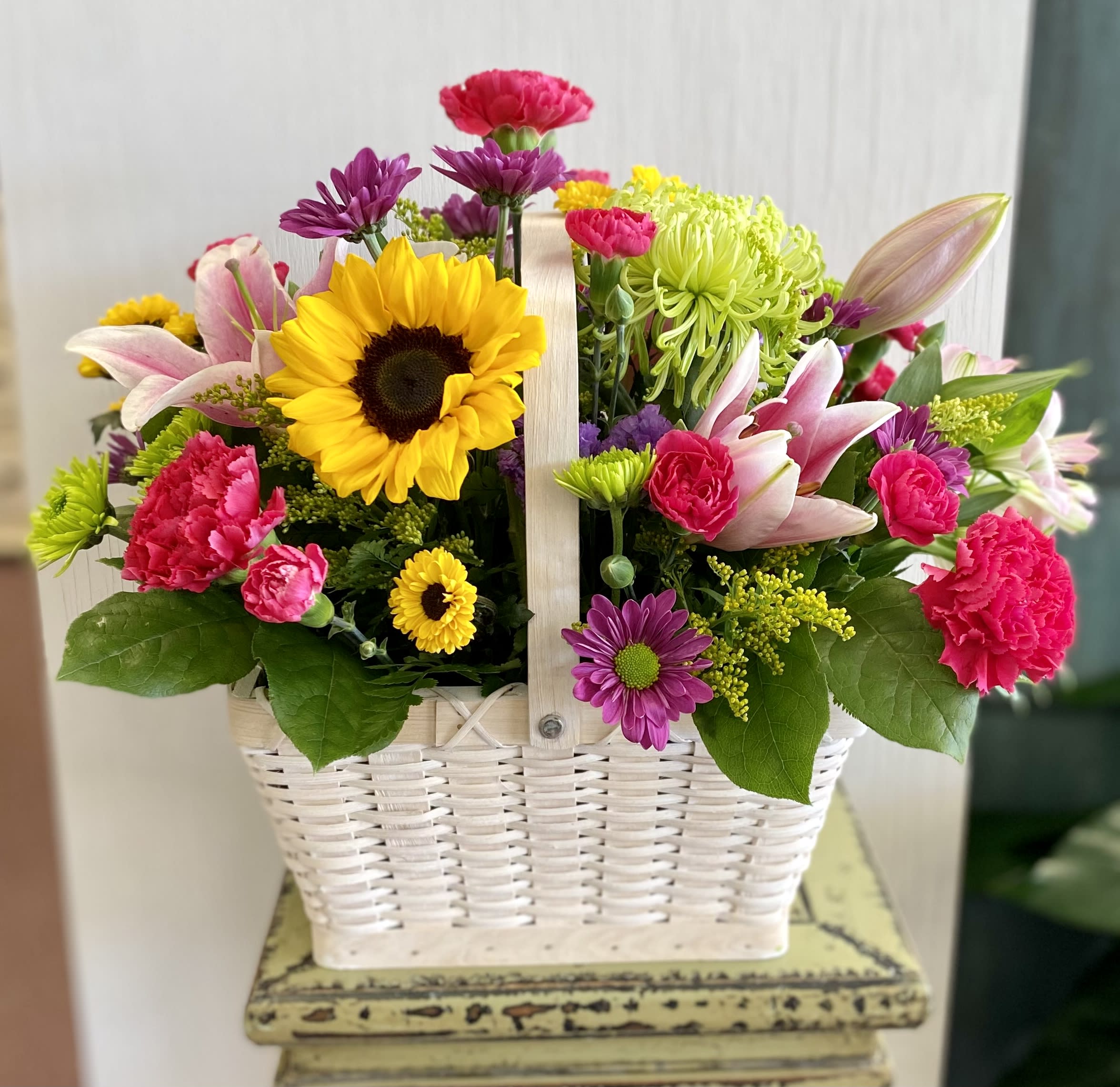 Mixed flowers in a white basket with a handle
