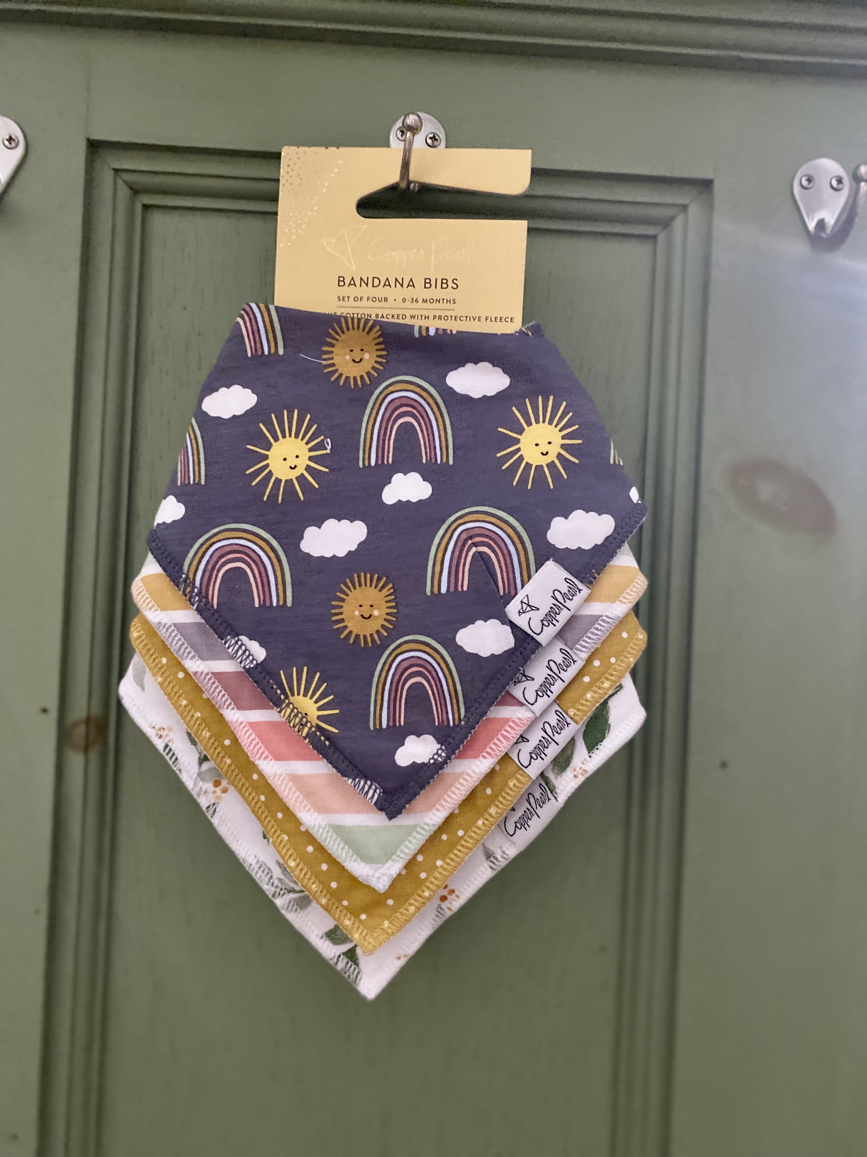Stack of patterned baby bandana bibs hanging on a hook