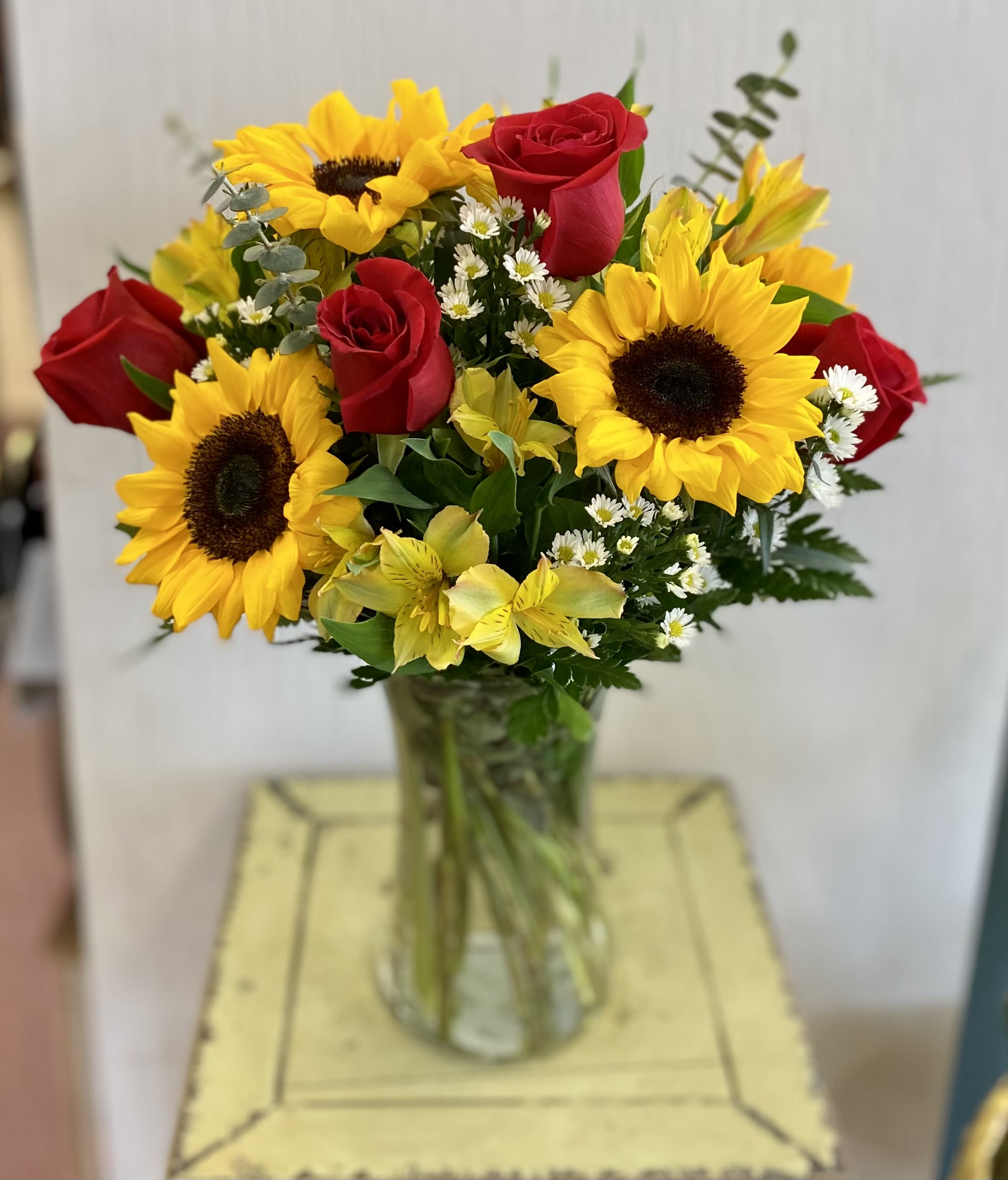 Bouquet of red roses and yellow sunflowers in a glass vase