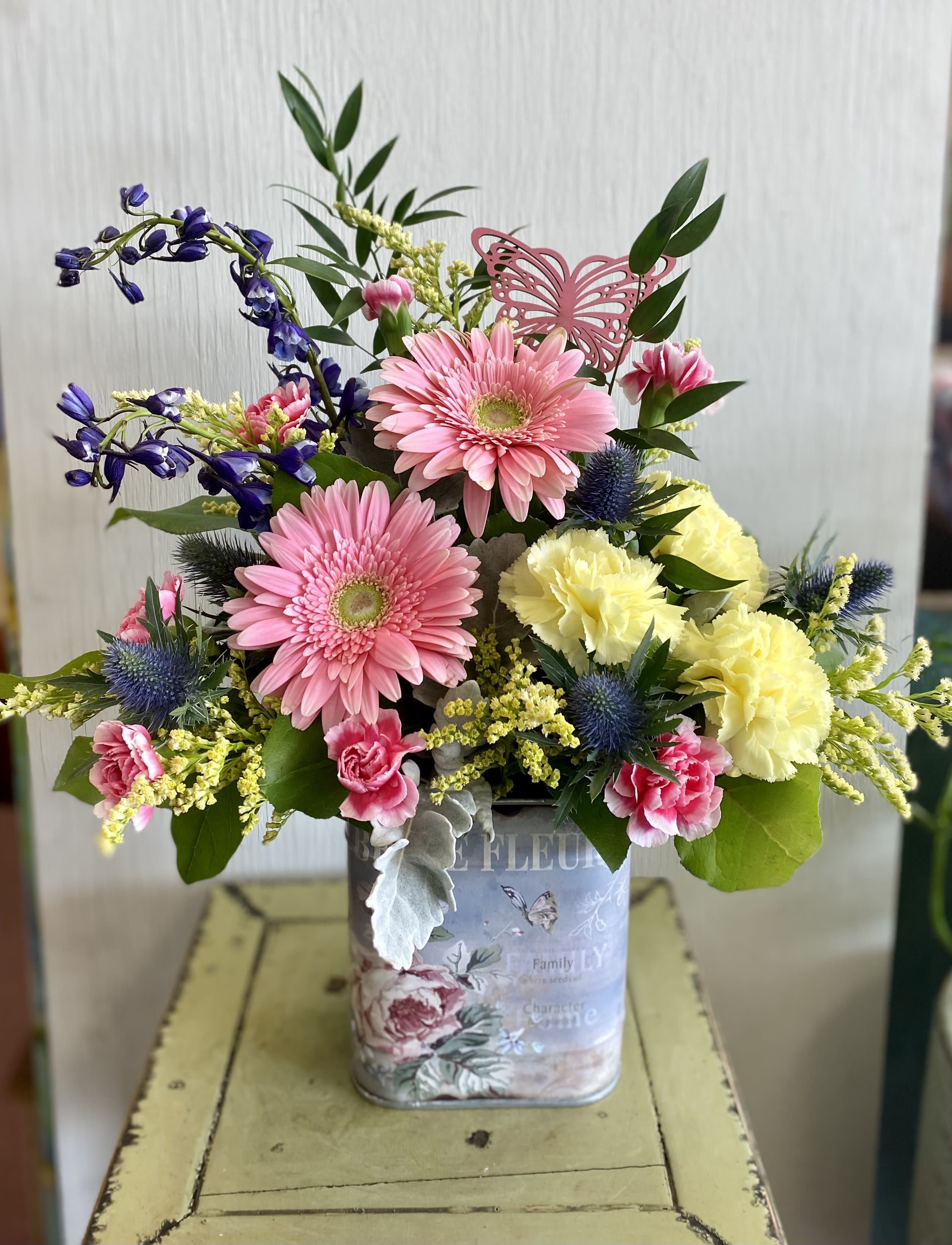 Mixed bouquet in a decorative tin container with pink and yellow flowers